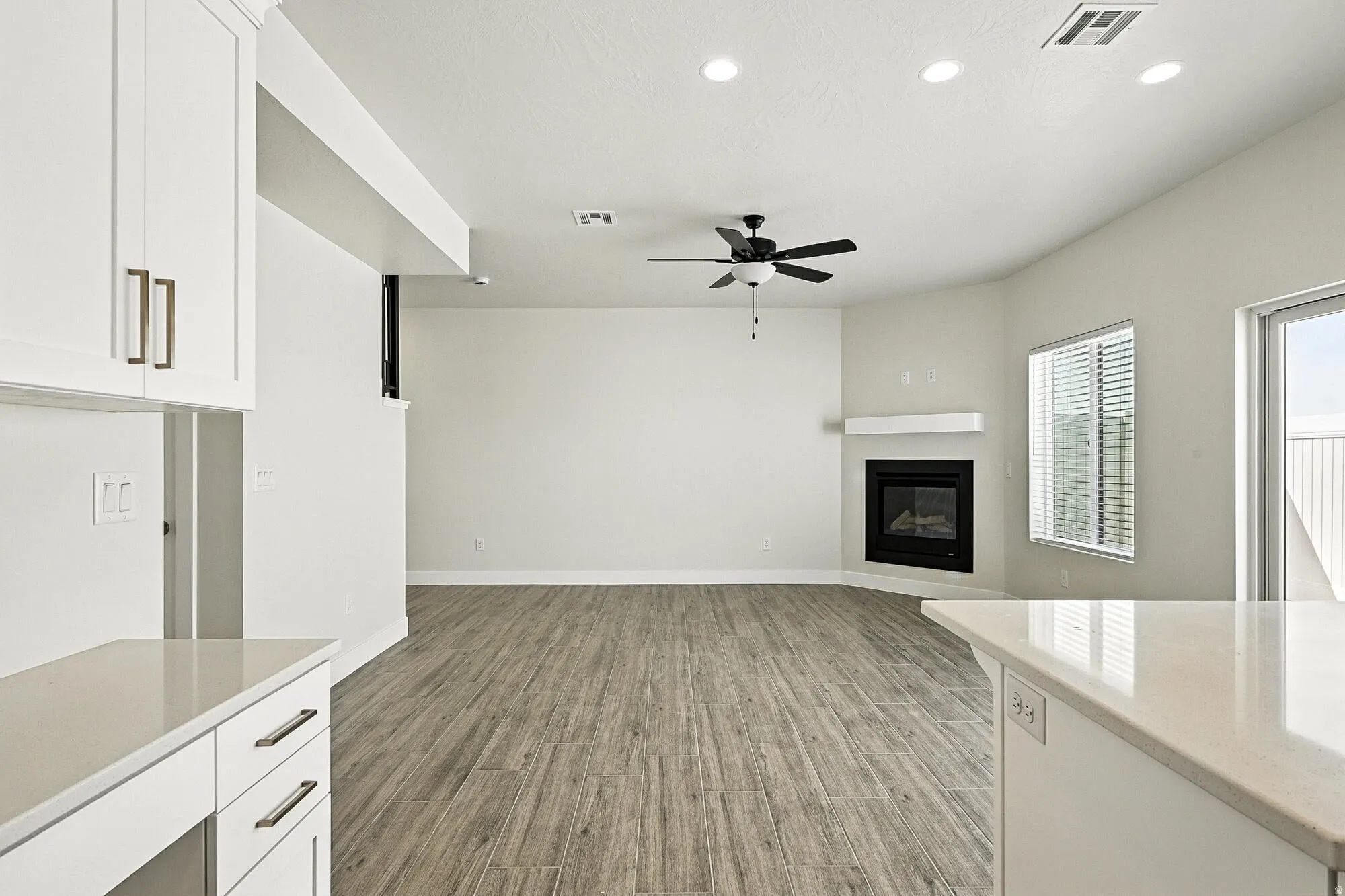 Unfurnished living room featuring light wood finished floors, a glass covered fireplace, ceiling fan, and recessed lighting