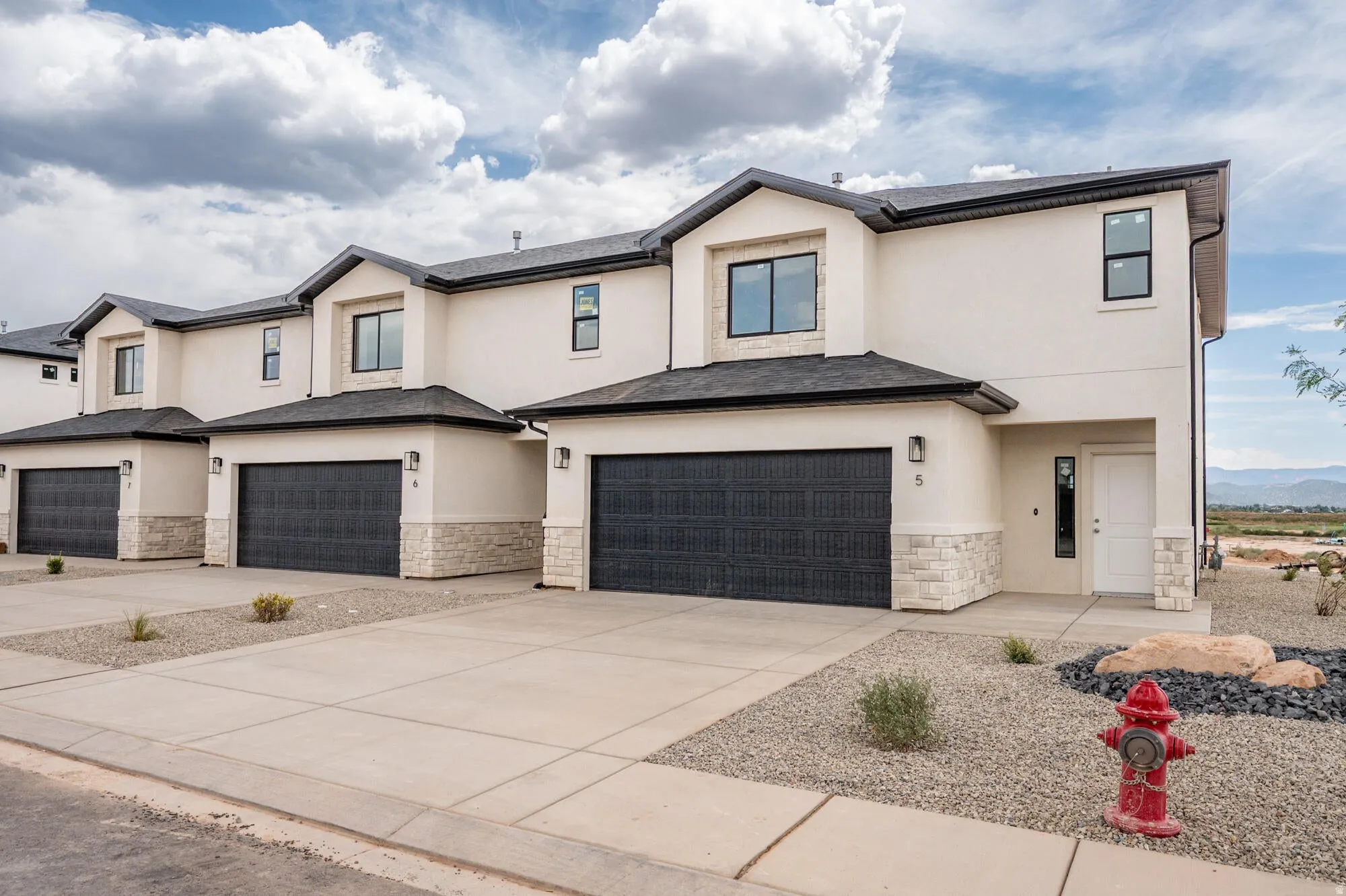 Modern farmhouse style home featuring stone siding, stucco siding, concrete driveway, and an attached garage