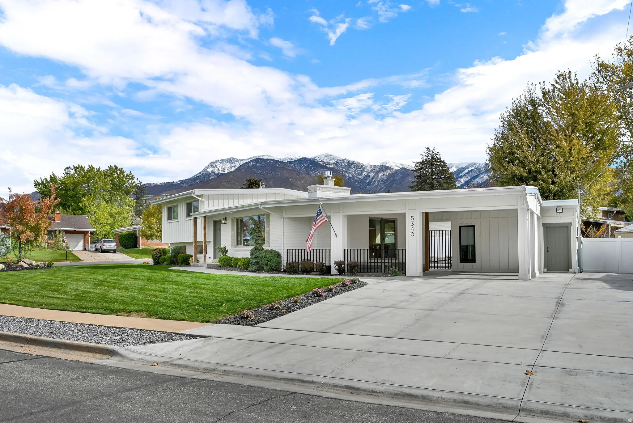 View of front facade featuring a porch, a mountain view, a front lawn, driveway, and a chimney