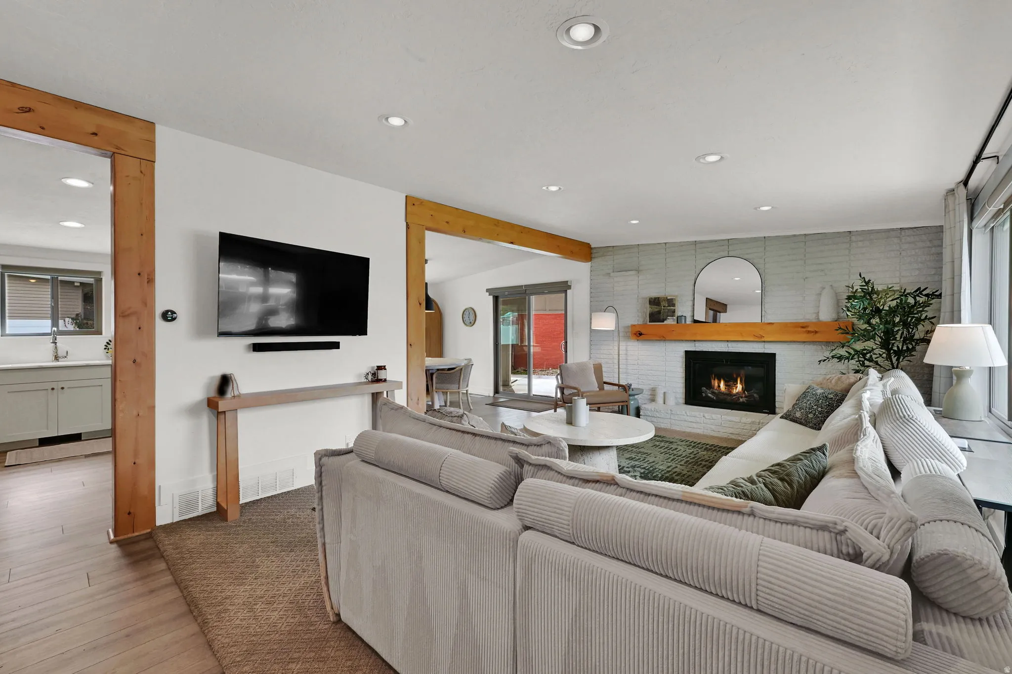 Living room with a brick fireplace, recessed lighting, and wood finished floors