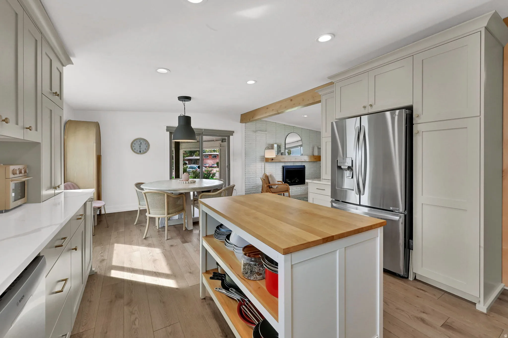 Kitchen featuring stainless steel appliances, pendant lighting, open shelves, light wood-style flooring, and open floor plan