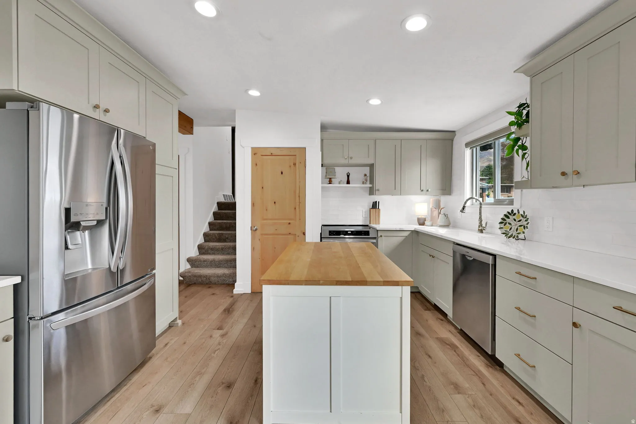 Kitchen featuring wooden counters, appliances with stainless steel finishes, light wood-type flooring, a center island, and recessed lighting