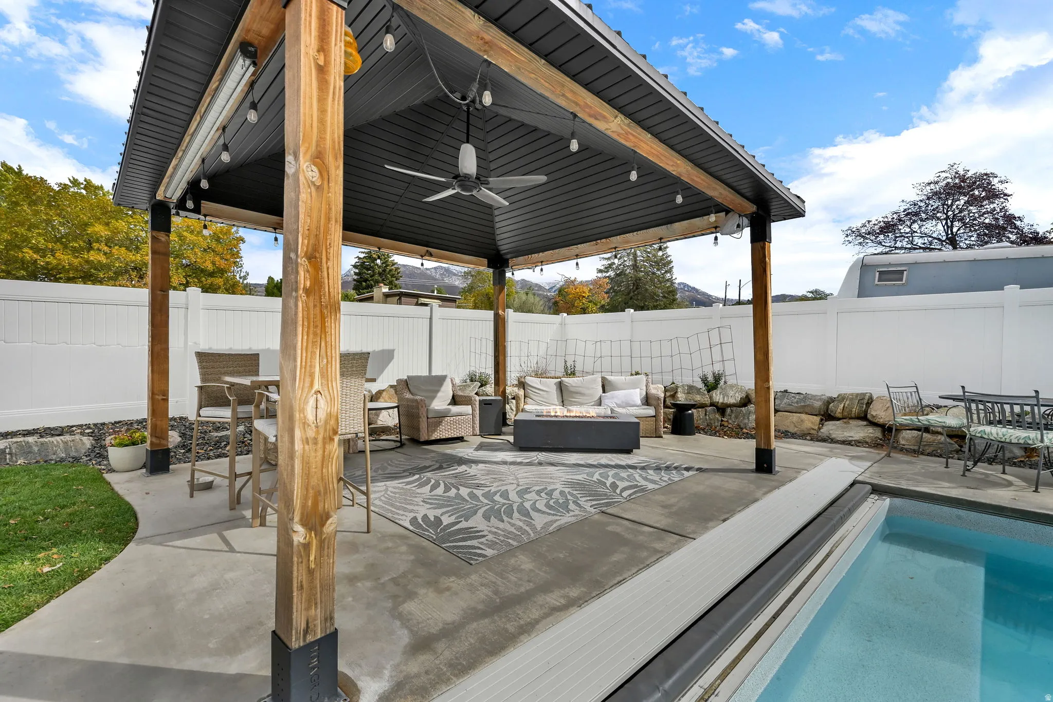 Fenced backyard with a ceiling fan, a patio, outdoor dining area, outdoor lounge area, and an outdoor pool