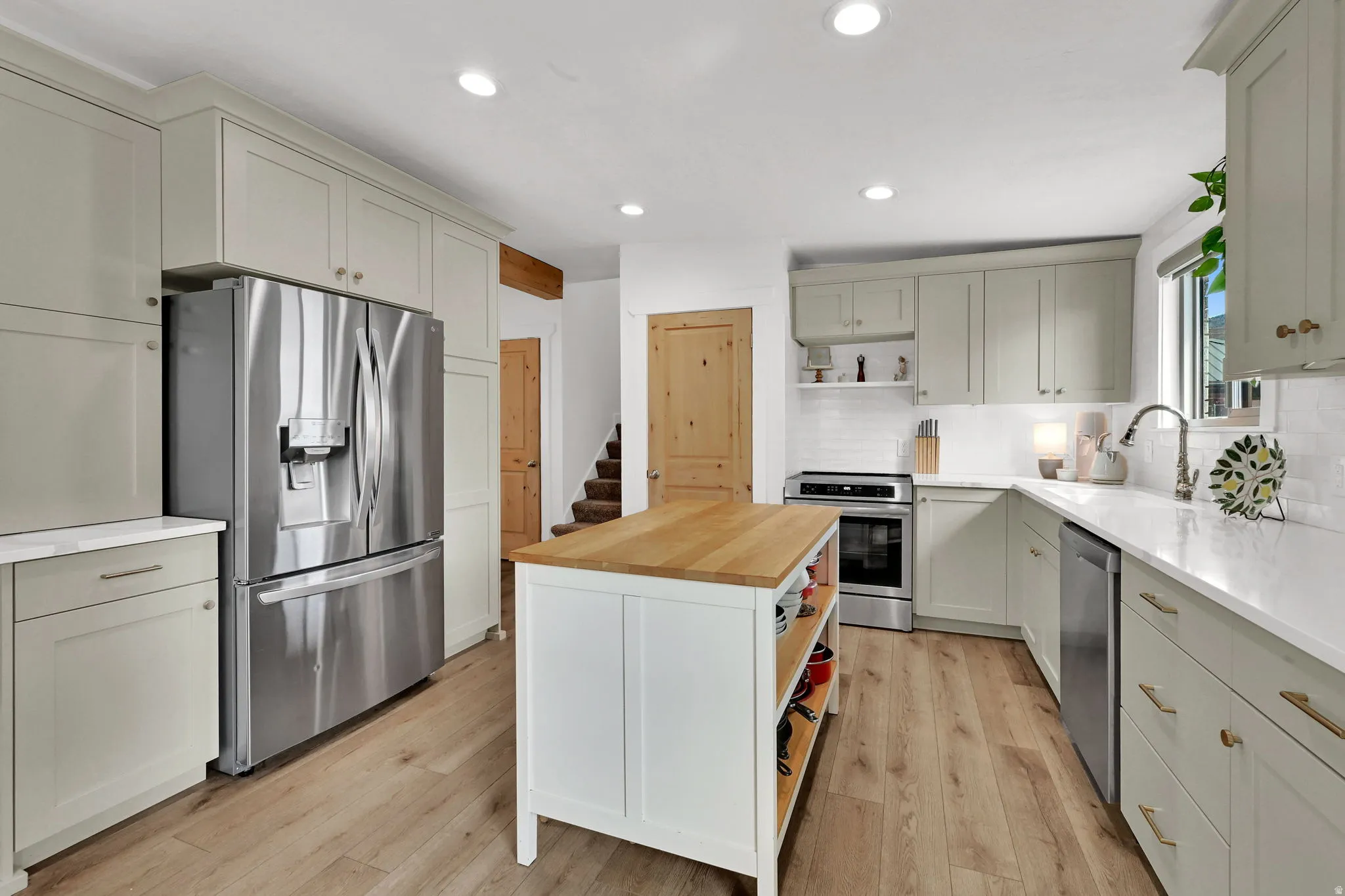 Kitchen featuring open shelves, butcher block countertops, appliances with stainless steel finishes, light wood-style flooring, and recessed lighting