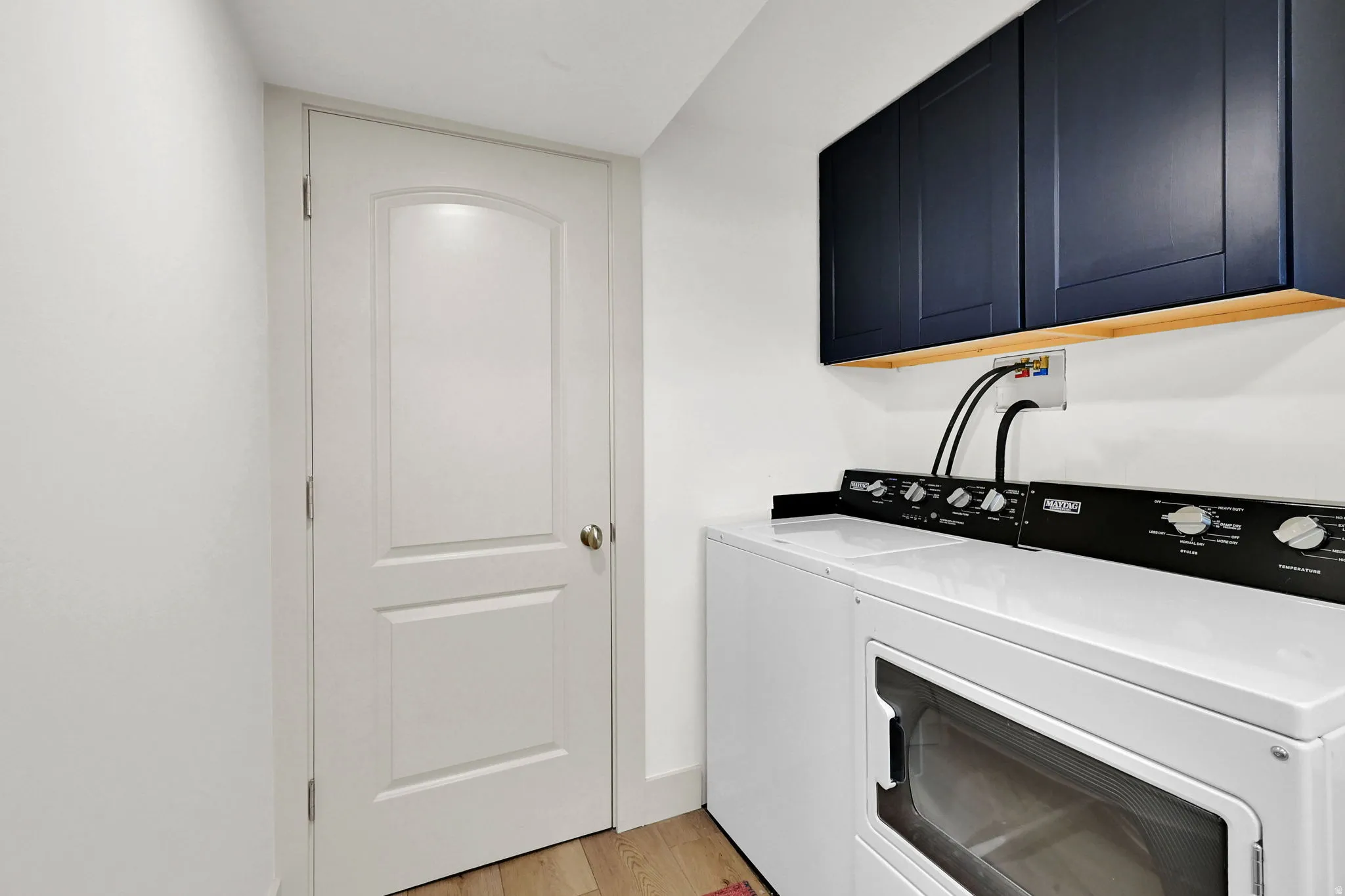 Laundry area featuring cabinet space, washing machine and dryer, and light wood-style floors