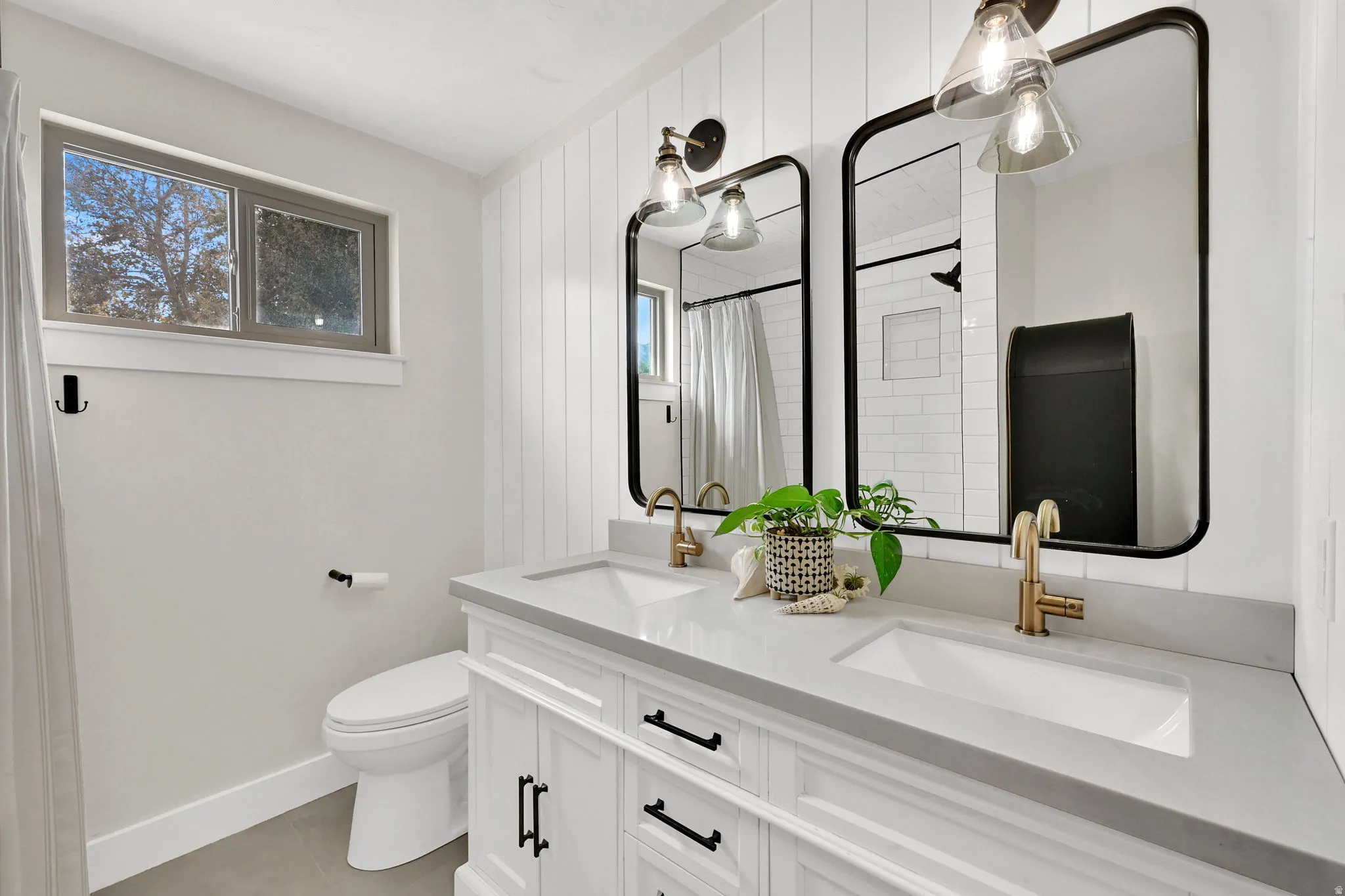 Full bath featuring a tile shower, double vanity, healthy amount of natural light, and light tile patterned floors