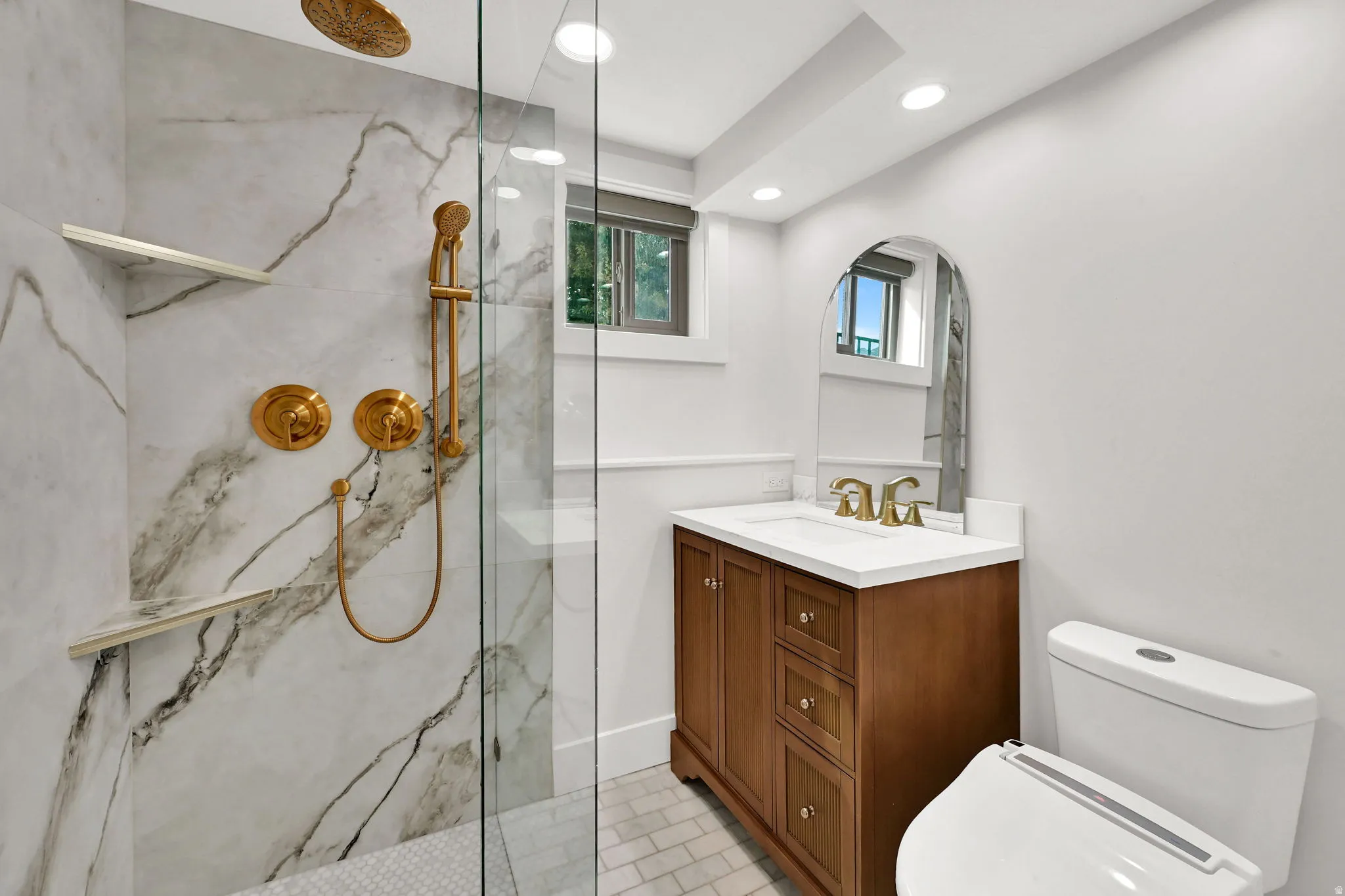 Bathroom featuring a marble finish shower, vanity, and recessed lighting
