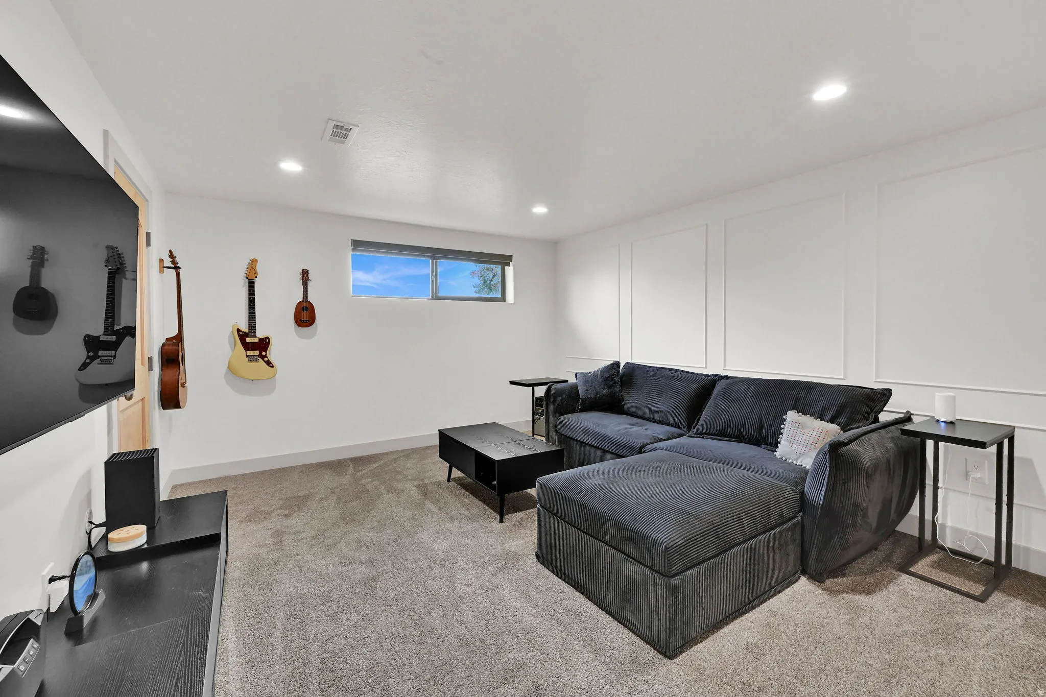 Living room featuring a decorative wall, light colored carpet, and recessed lighting