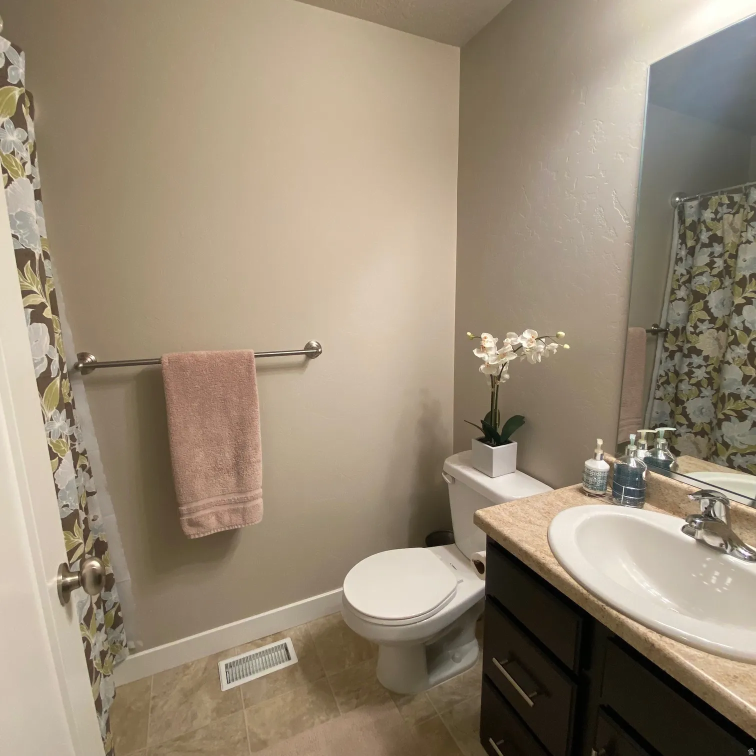 Bathroom featuring a shower with curtain, vanity, a textured wall, and light tile patterned floors