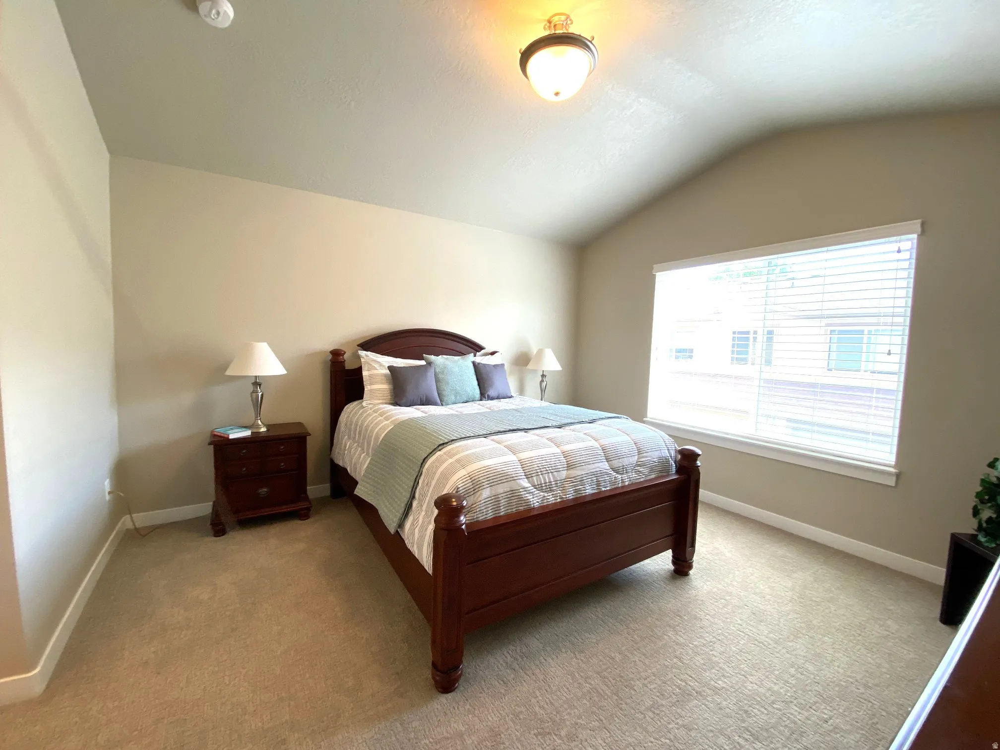 Carpeted bedroom with vaulted ceiling and baseboards