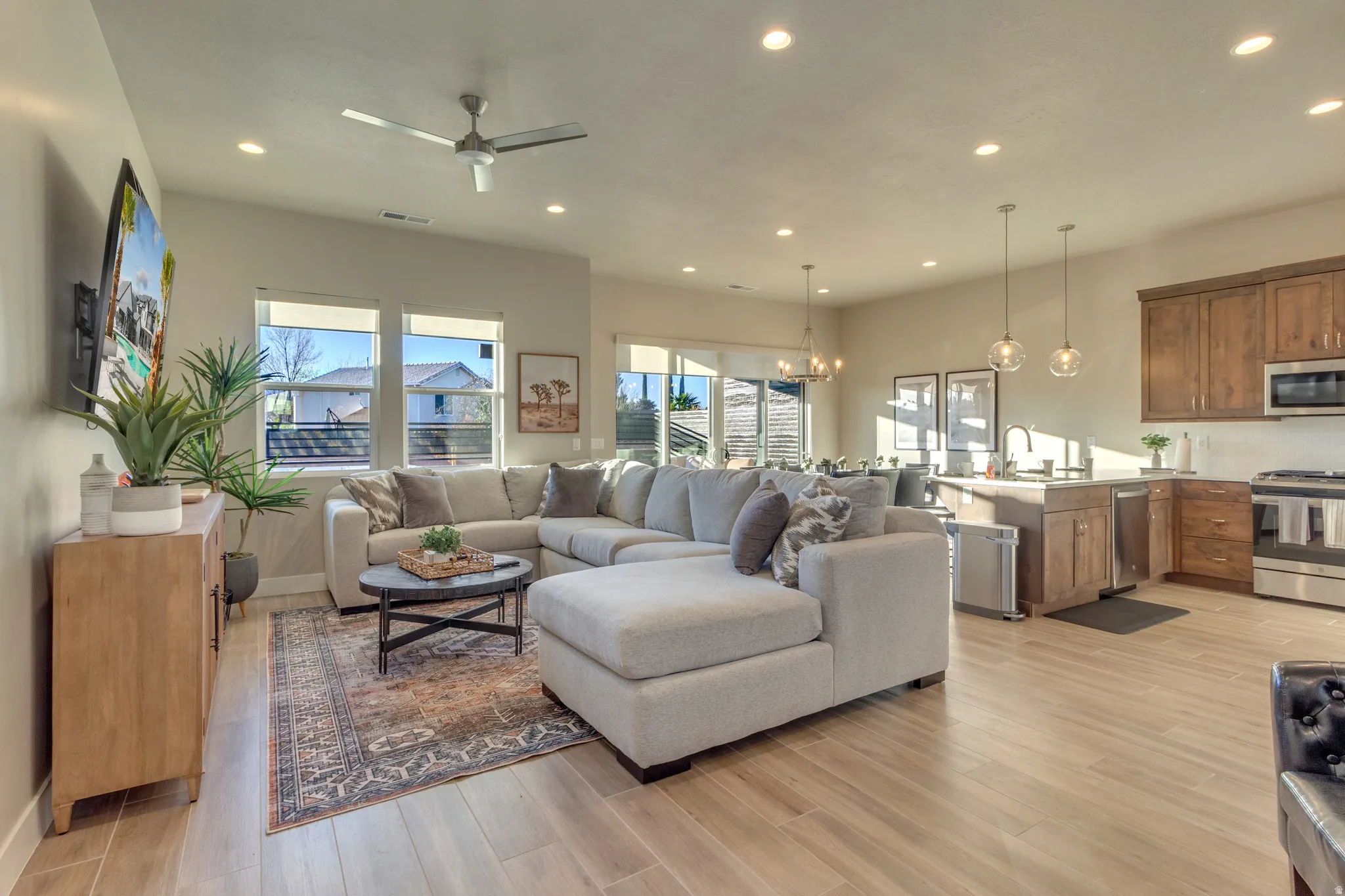 Living room featuring a ceiling fan, light wood-style flooring, and hanging lights