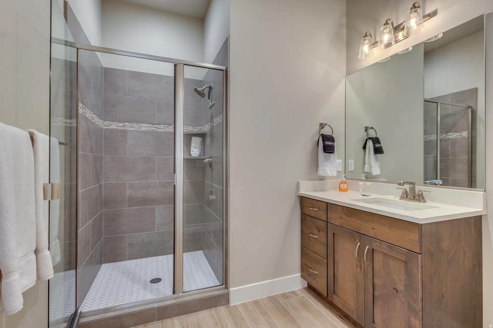 Bathroom with vanity, a shower stall, and wood finish floors