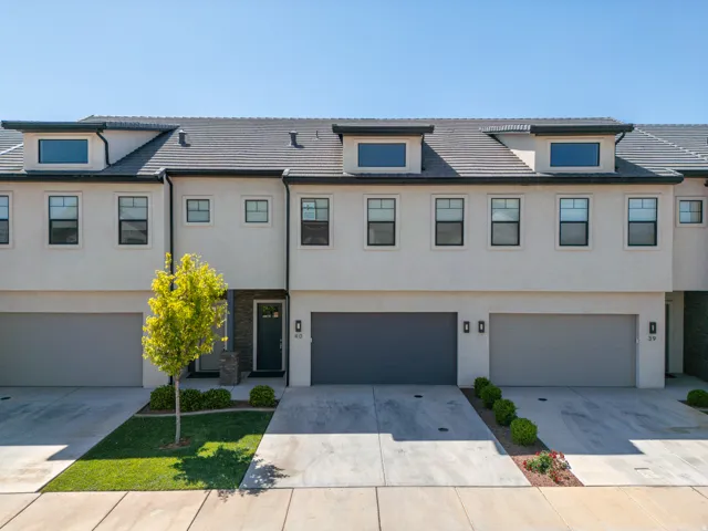 View of front of home with stucco siding, an attached garage, and concrete driveway