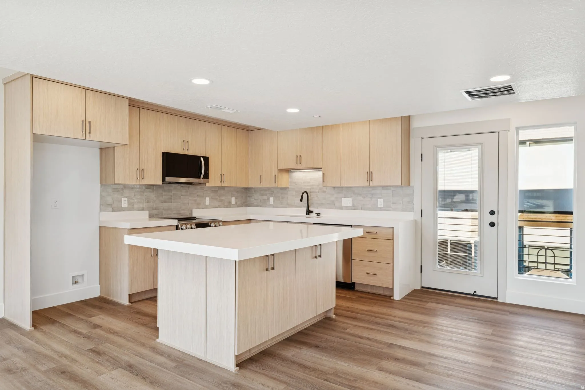 Kitchen with light wood finish cabinets, a kitchen island, stainless steel appliances, light wood-style floors, and recessed lighting