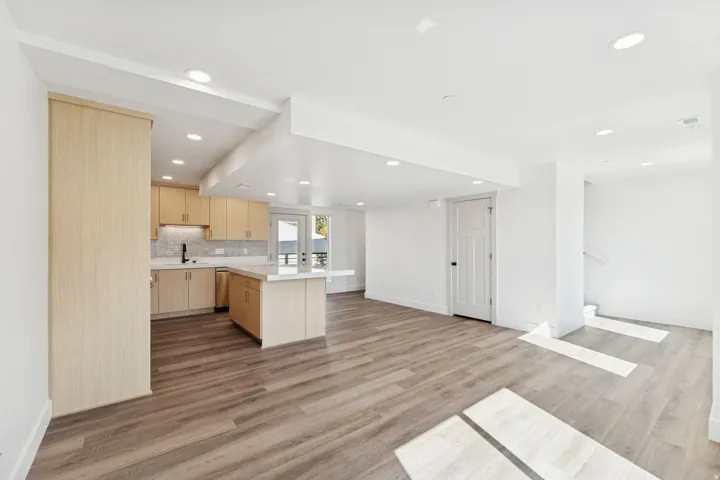 Kitchen with light wood finish cabinetry, light countertops, light wood-style floors, open floor plan, and recessed lighting