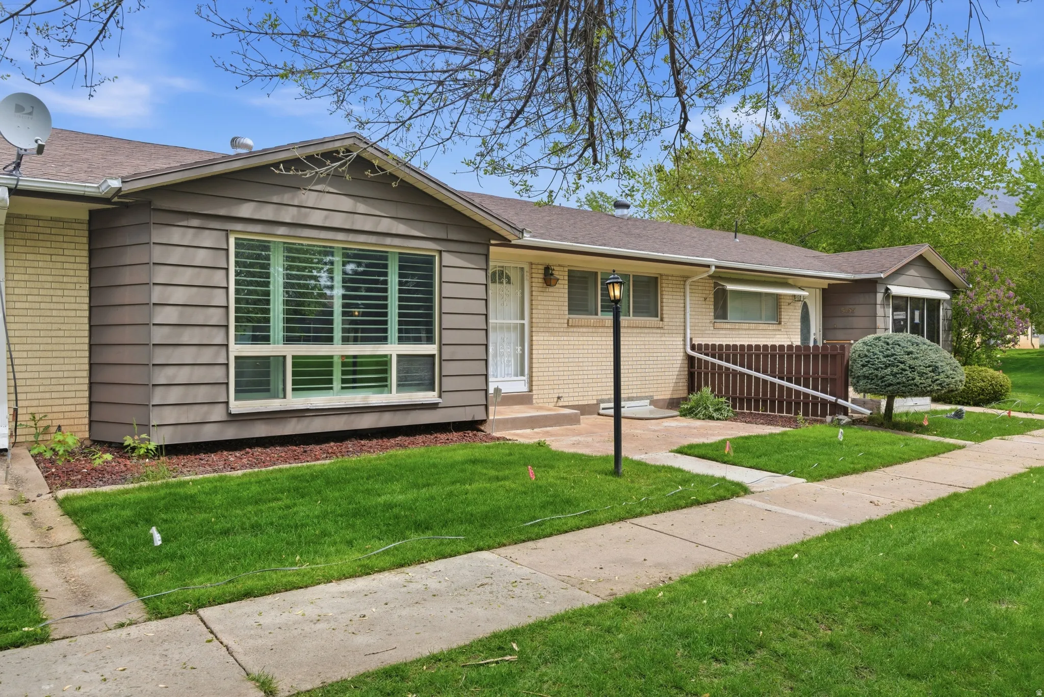 Ranch-style townhouse featuring brick siding, a front lawn, and a shingled roof