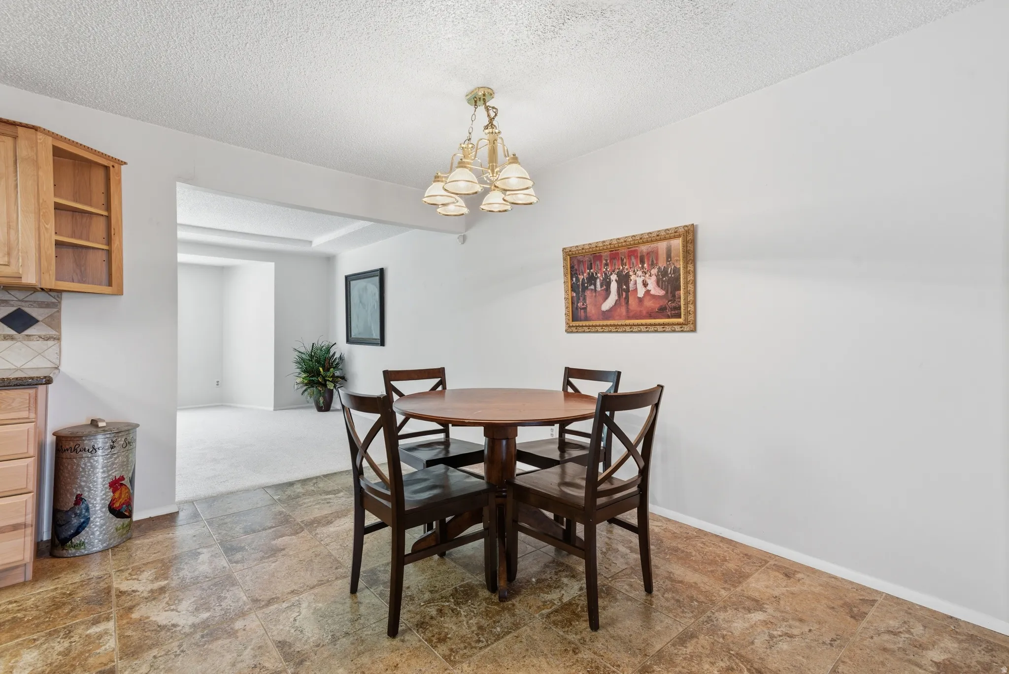 Dining area with a textured ceiling, light stone finish floors, and a chandelier