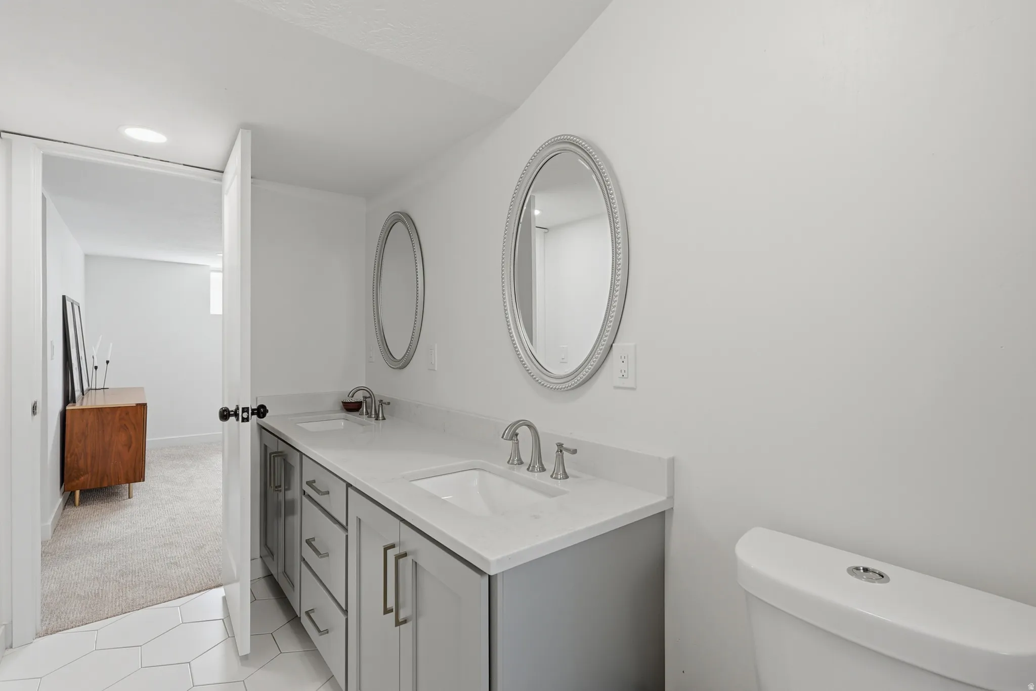 Bathroom featuring double vanity, light colored carpet, light tile patterned floors, and recessed lighting