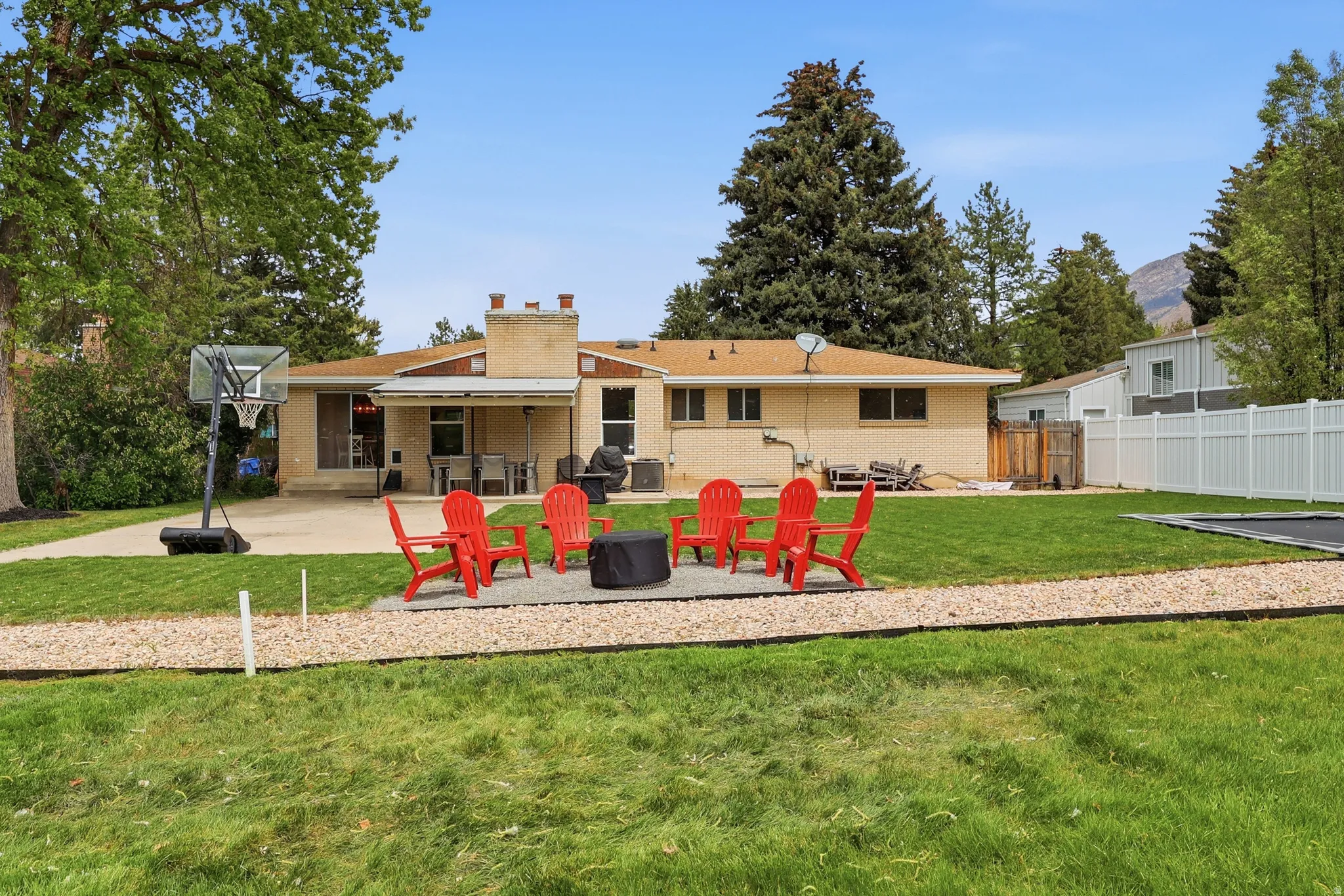 Rear view of property featuring a patio, brick siding, a fire pit, and a chimney