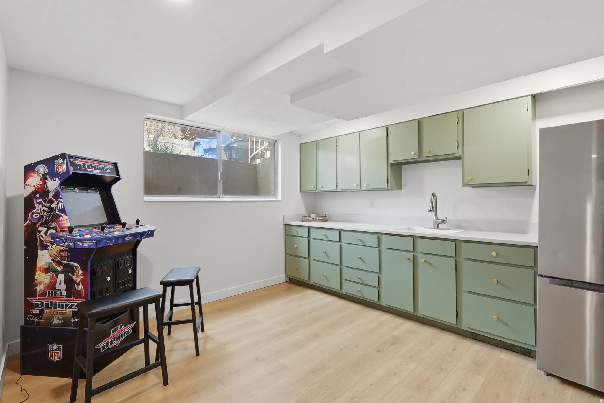 Kitchen with green cabinets, light countertops, freestanding refrigerator, and light wood finished floors