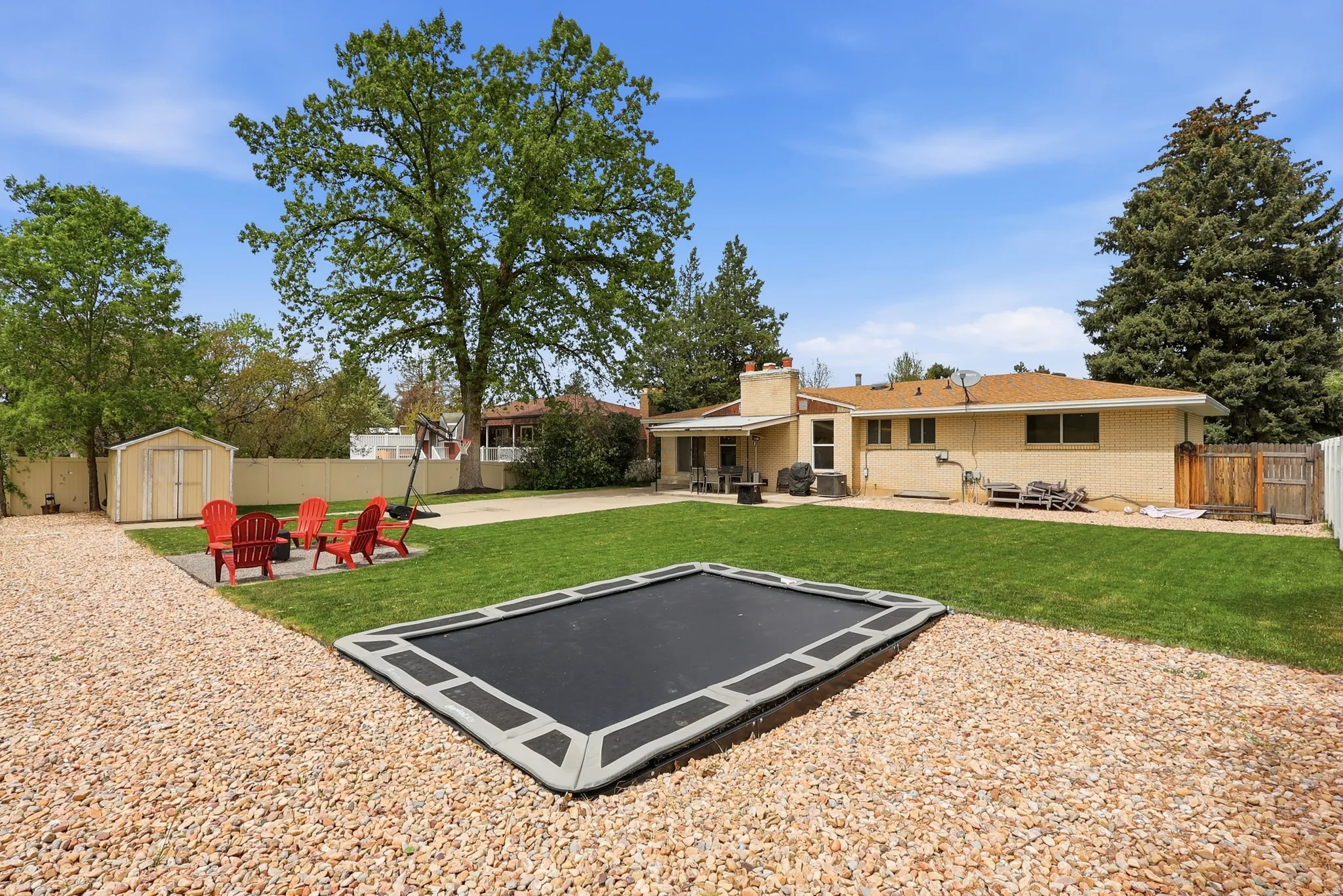 View of sport court featuring a patio, a fenced backyard, and a storage unit