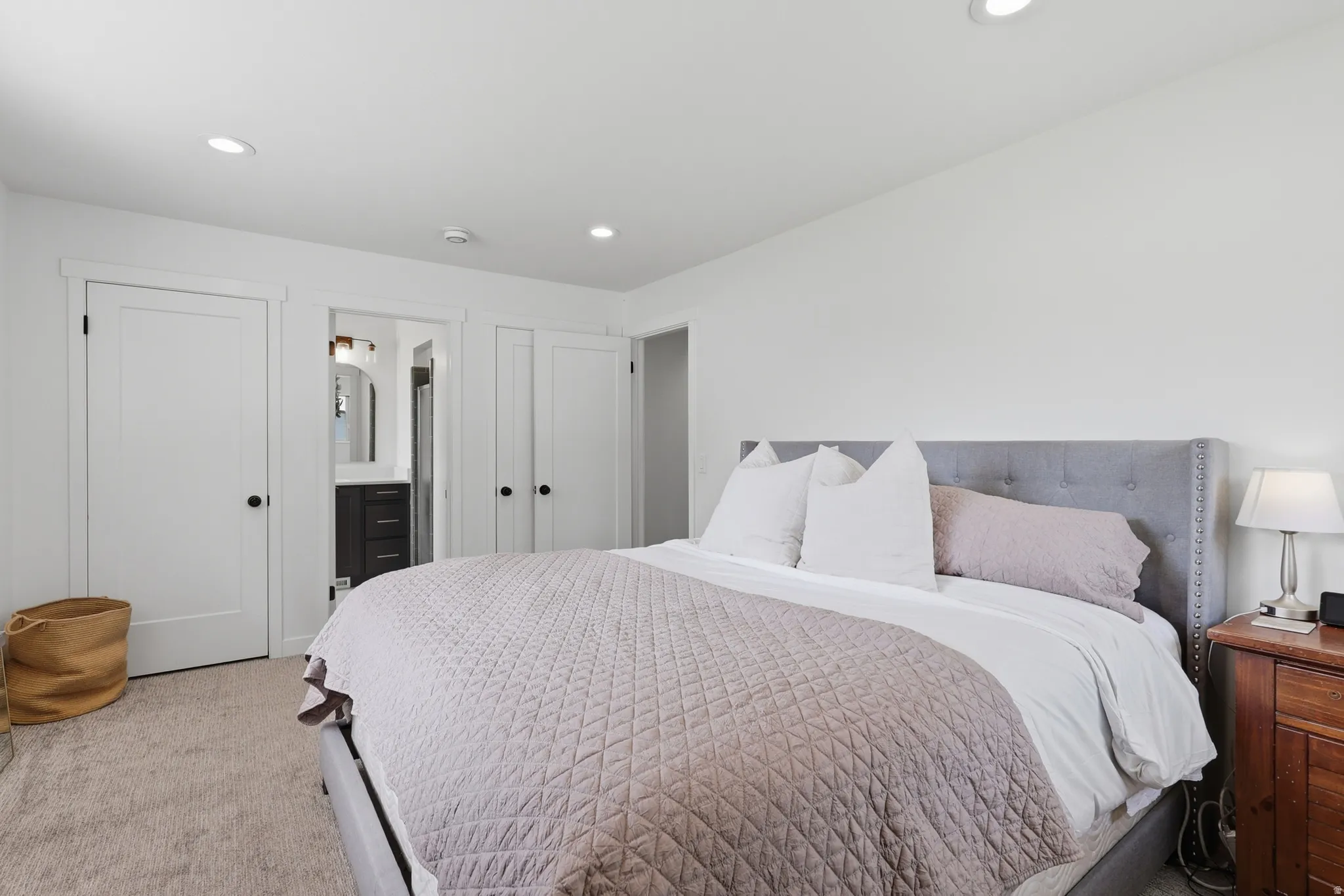 Bedroom with light colored carpet, recessed lighting, and ensuite bathroom