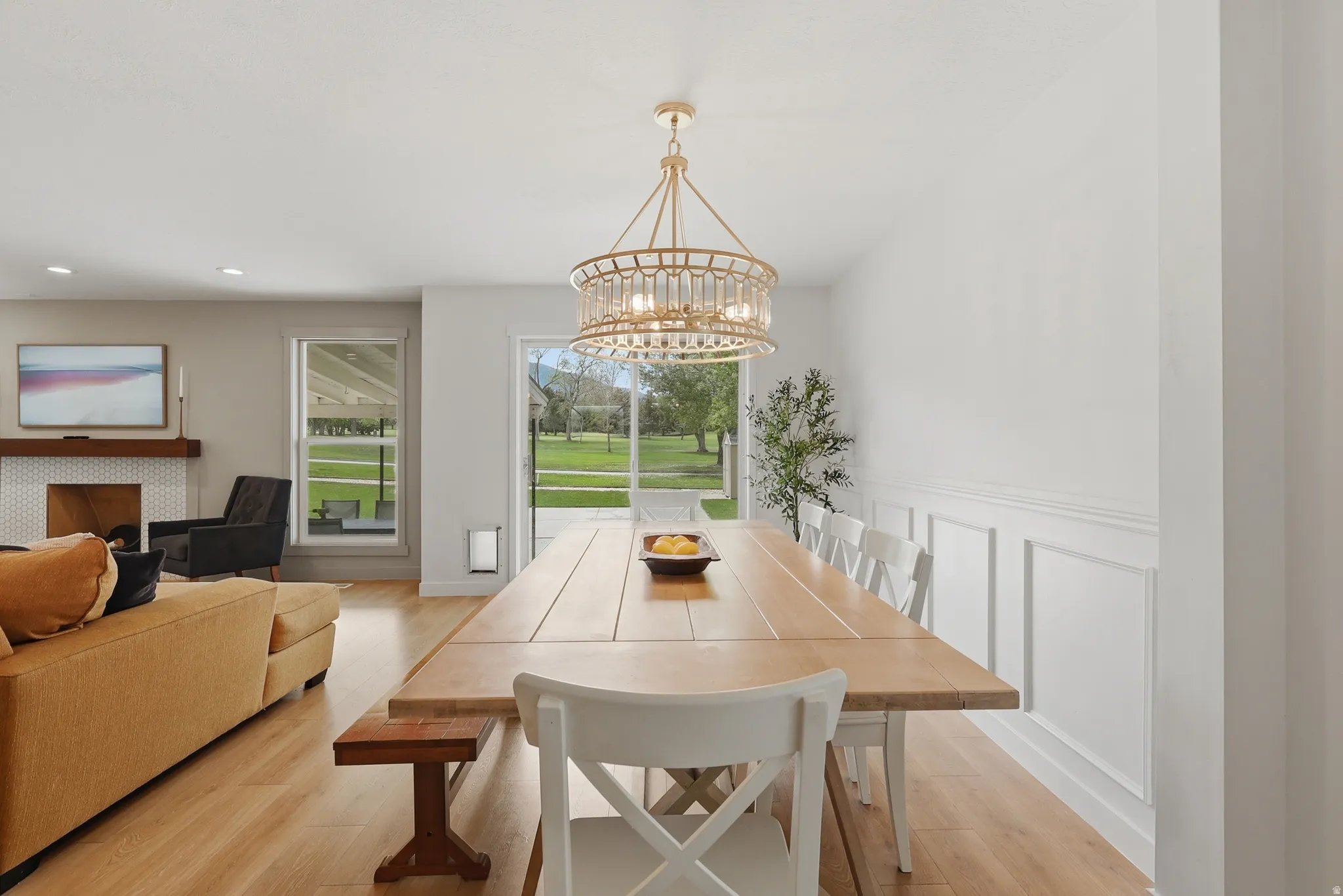 Dining space featuring a chandelier, light wood-style floors, a decorative wall, and wainscoting