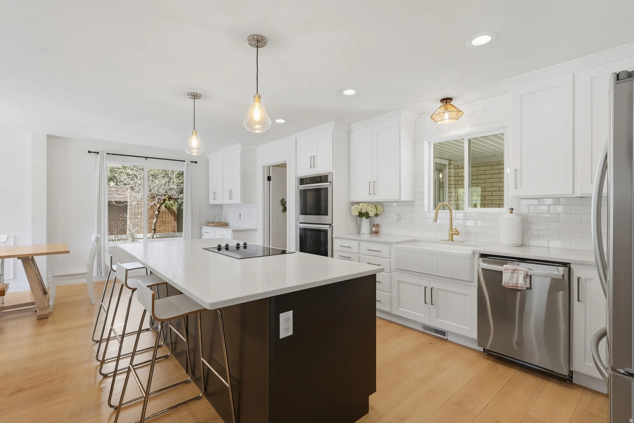 Kitchen featuring two tone cabinetry, a center island, light wood-style flooring, stainless steel appliances, and a breakfast bar