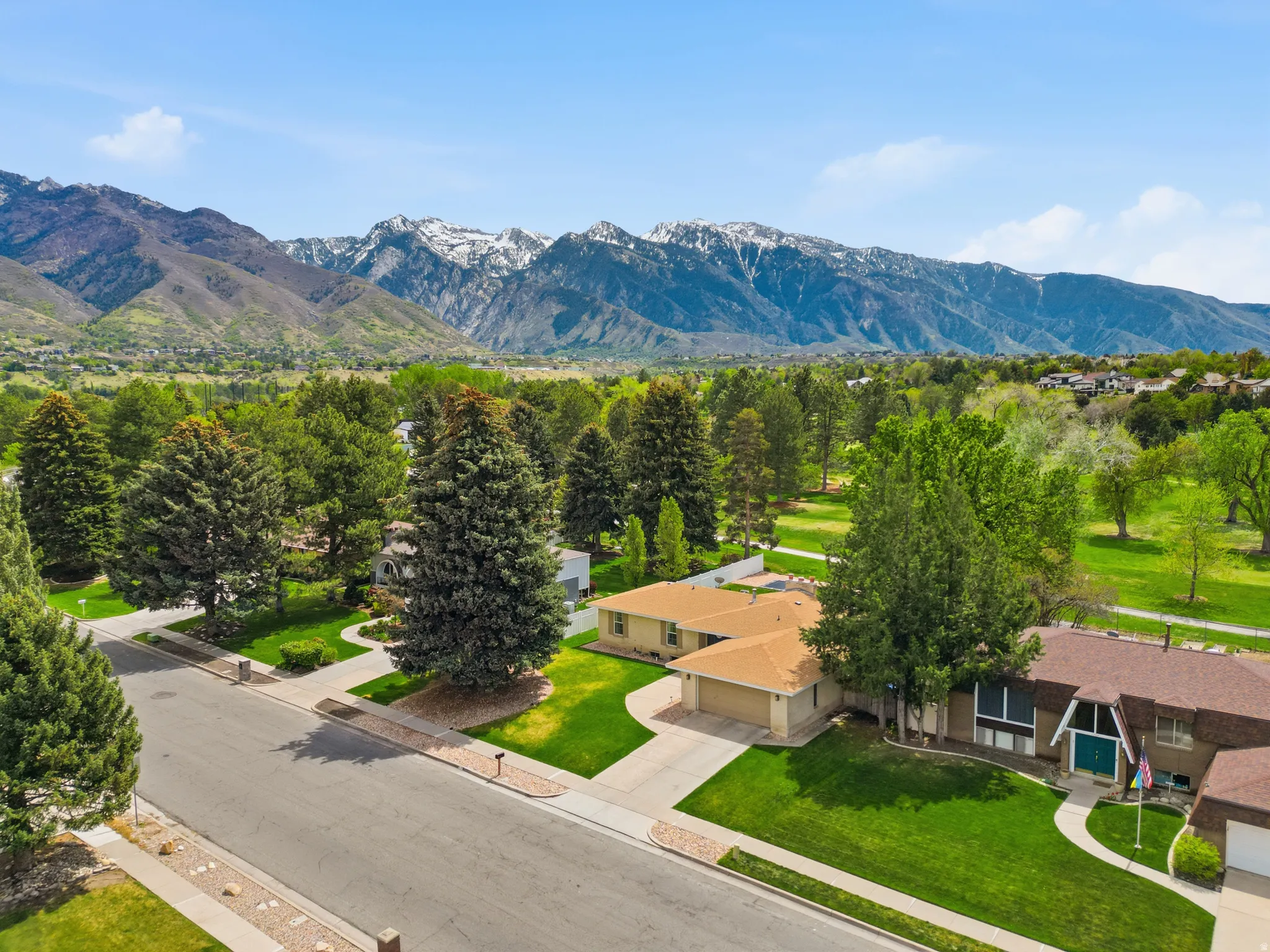 Aerial perspective of suburban area featuring a golf course and mountain backdrop