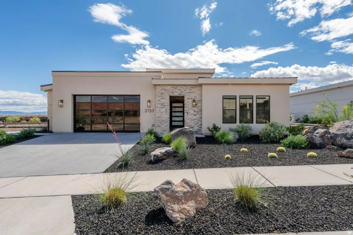Contemporary home with a garage, driveway, stucco siding, and stone siding