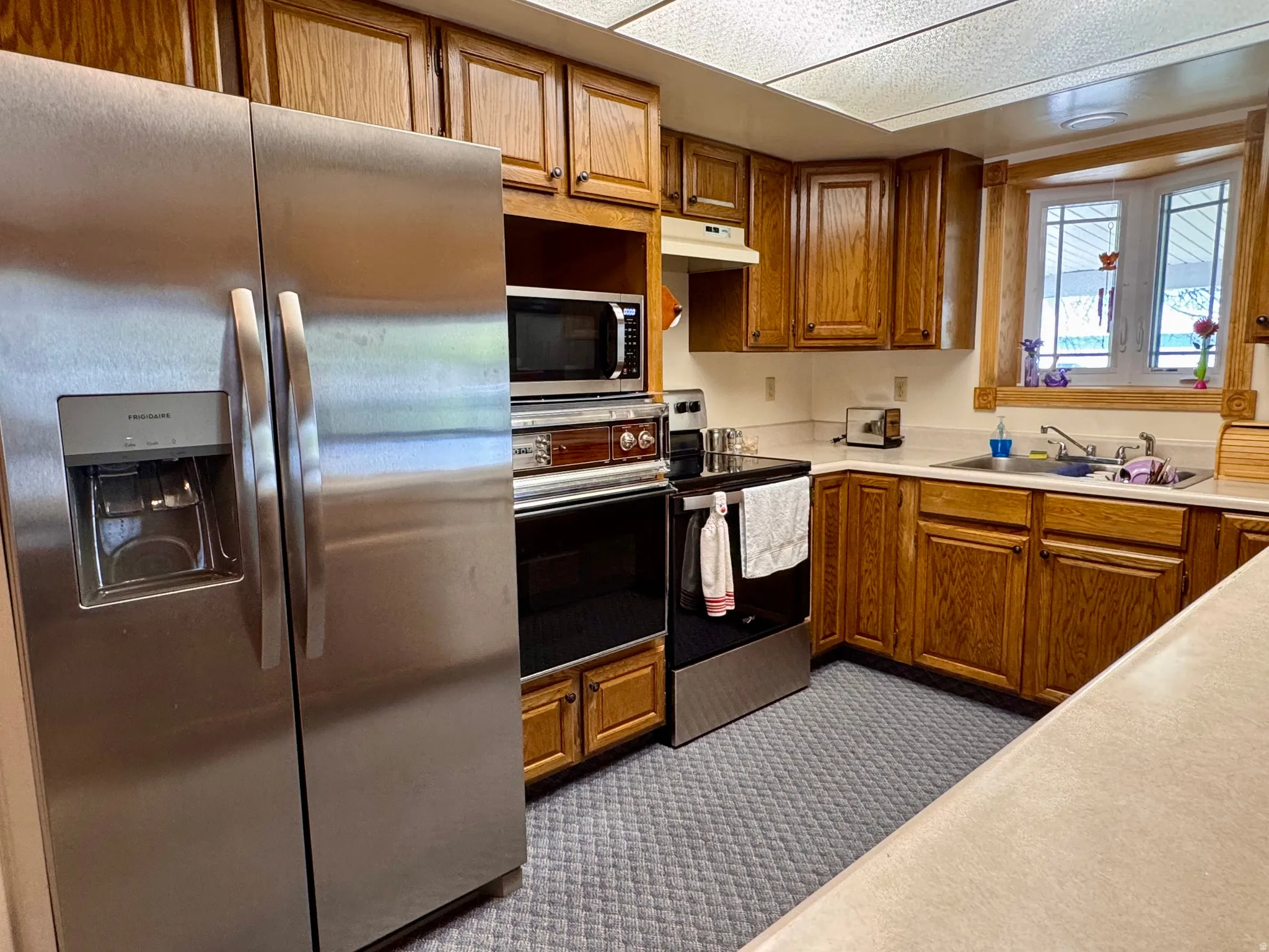 Kitchen with stainless steel appliances, wood finish cabinets, and light countertops