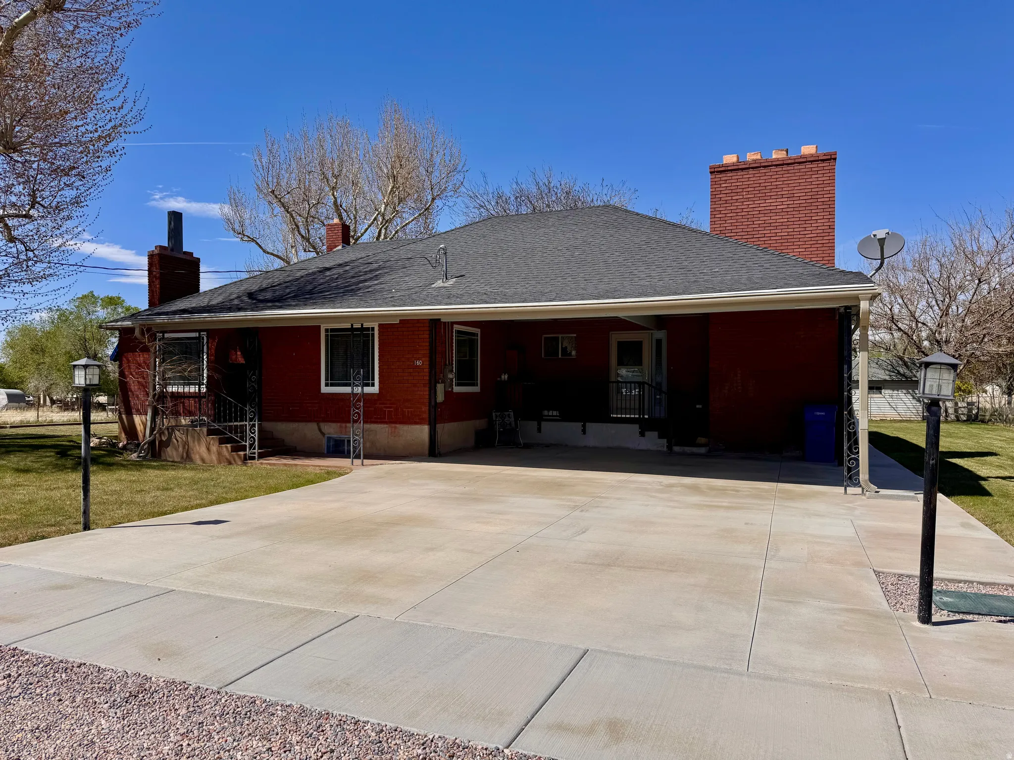 Rear view of property with a chimney, a lawn, roof with shingles, and brick siding