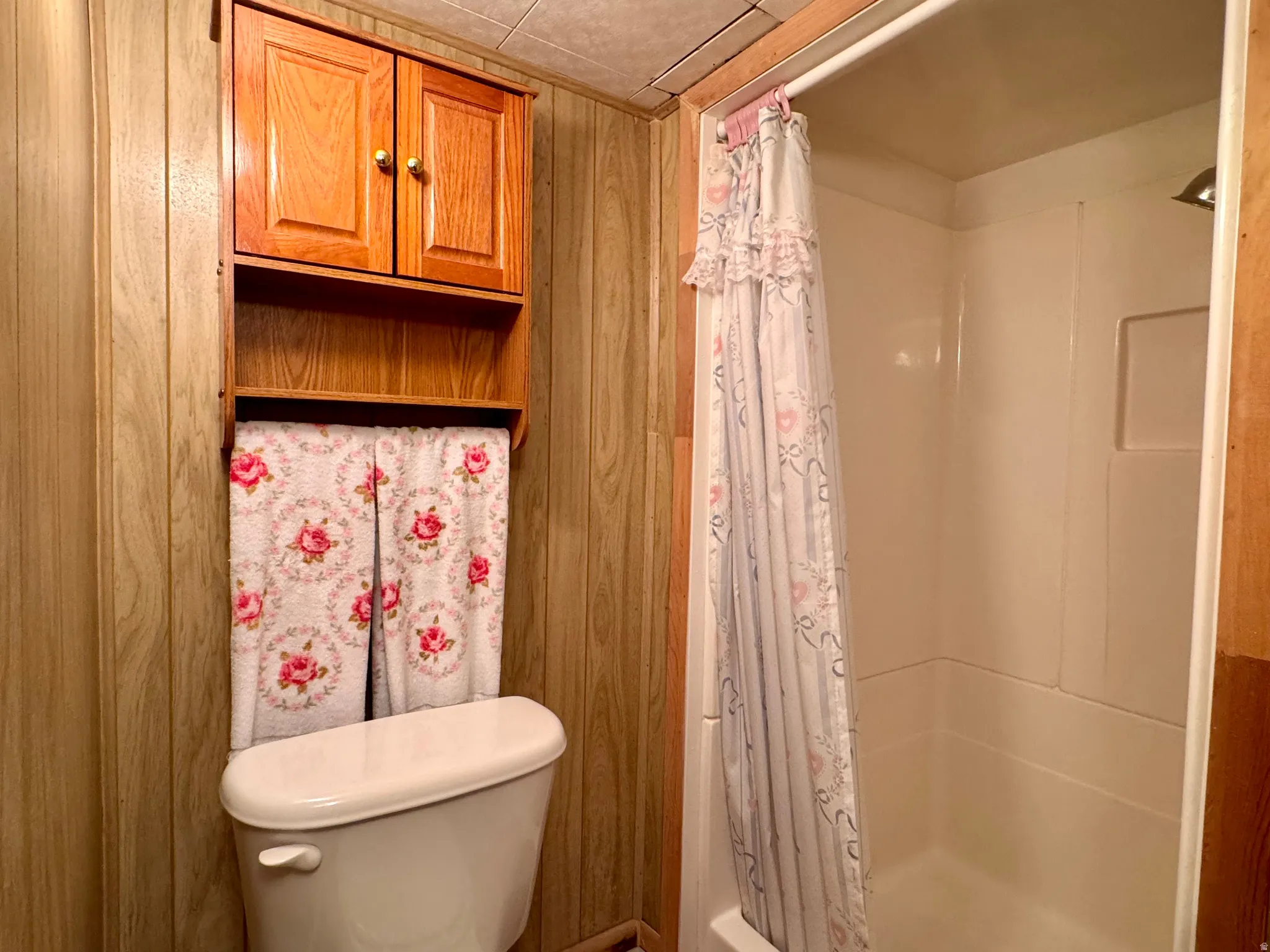 Full bathroom with a stall shower and wood walls
