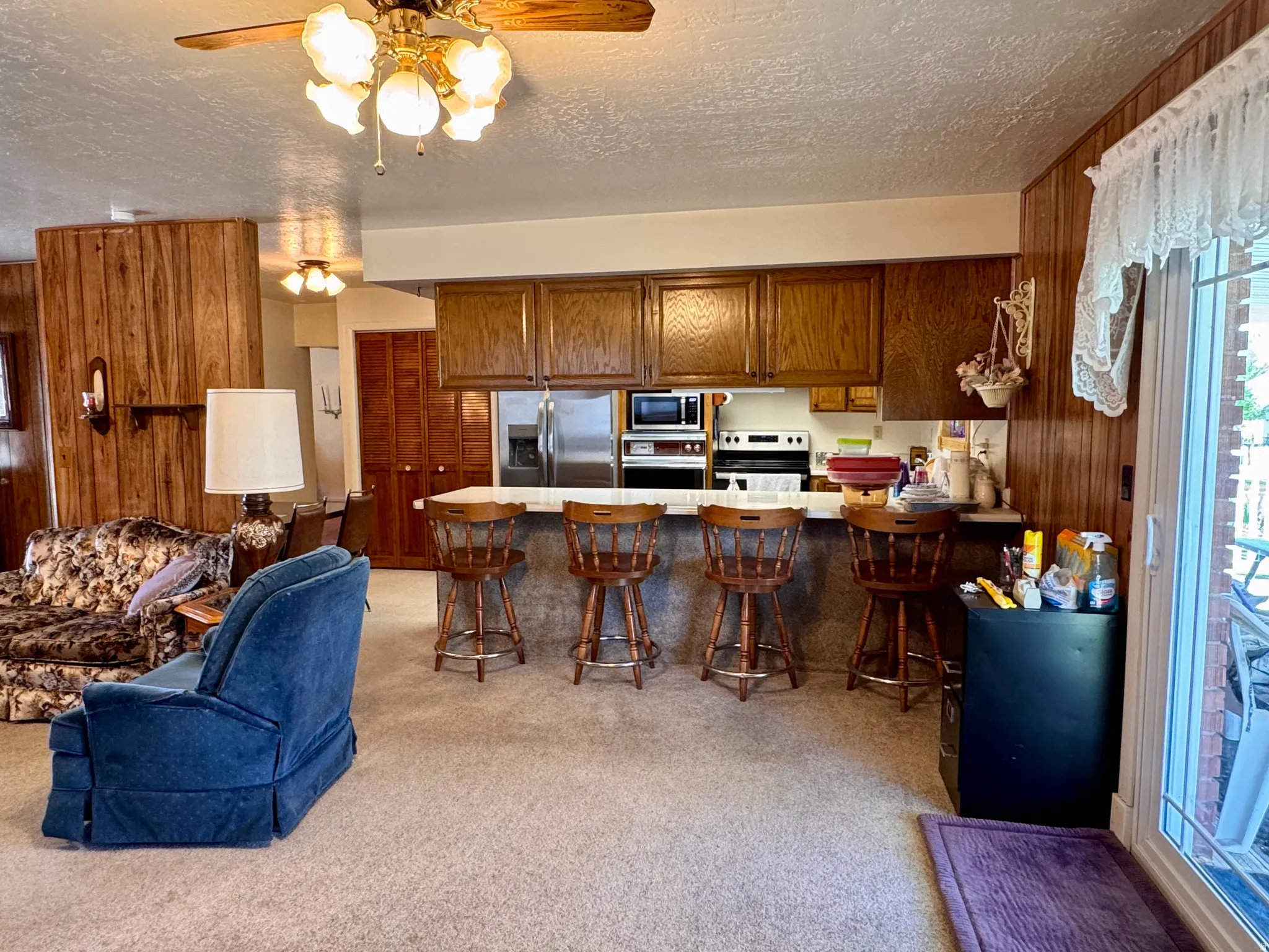 Kitchen featuring a breakfast bar, a peninsula, light countertops, ceiling fan, and wood finish cabinetry