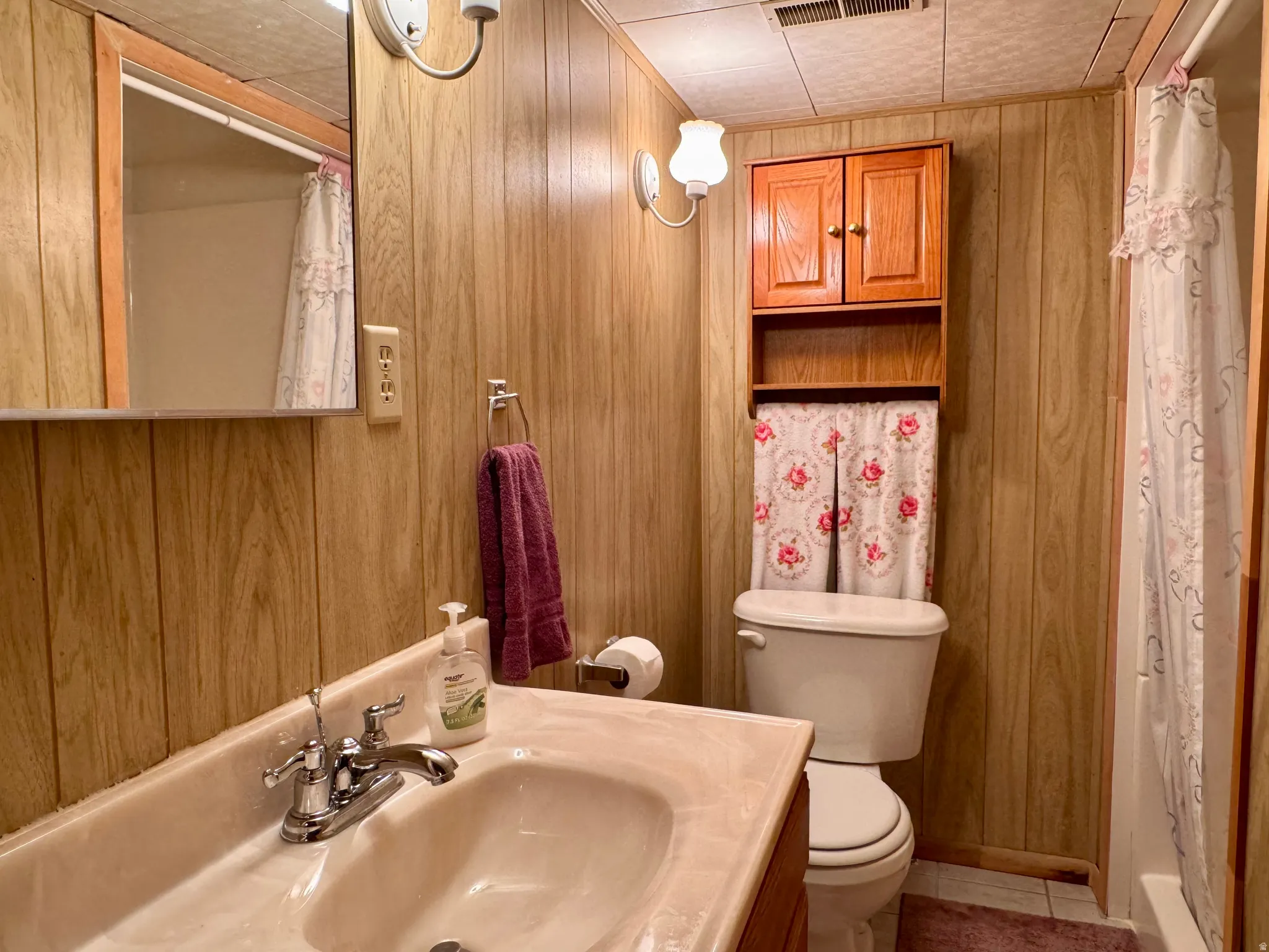 Bathroom with a shower stall, vanity, wood walls, and tile patterned floors