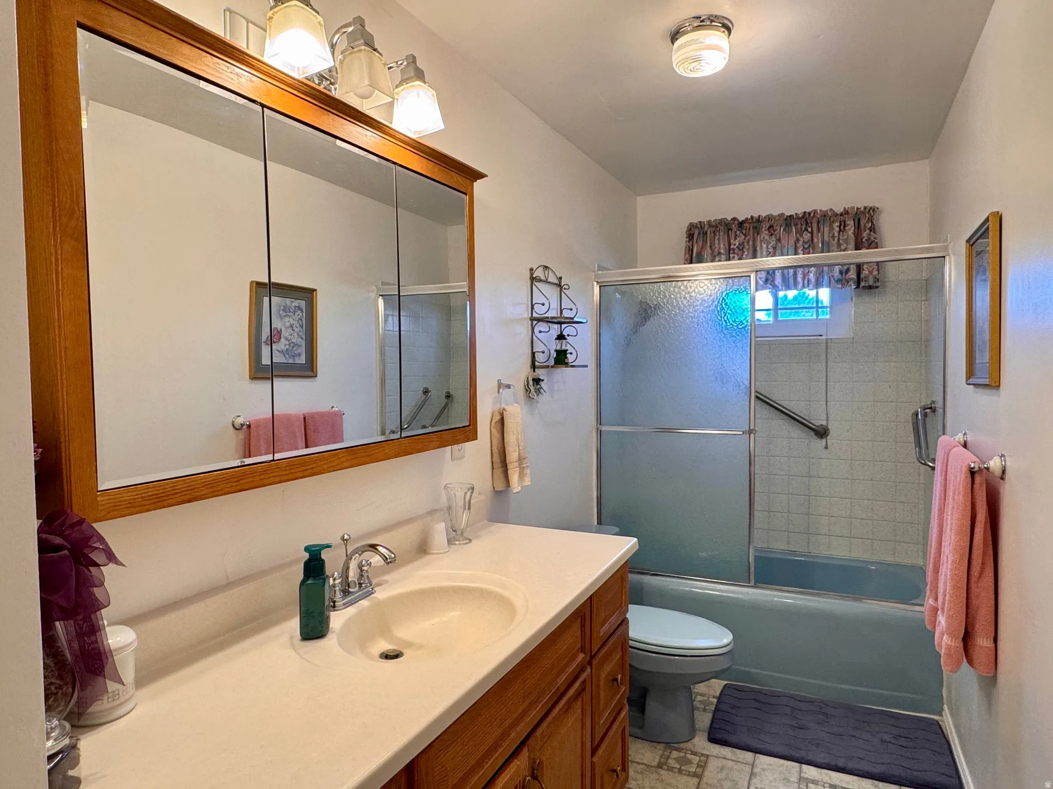 Bathroom featuring vanity and combined bath / shower with glass door