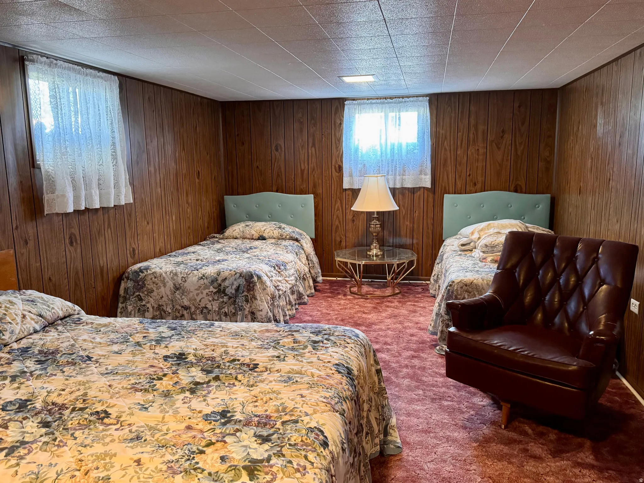 Carpeted bedroom featuring wood walls