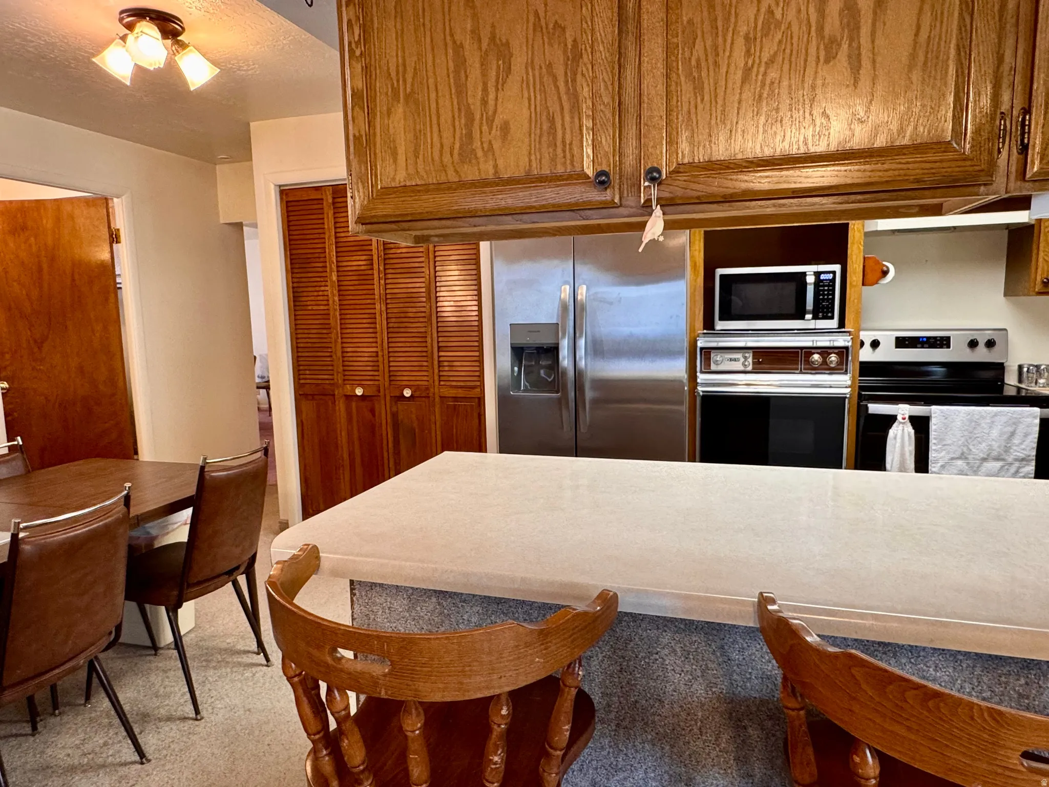 Kitchen with wood finish cabinets, stainless steel appliances, and light countertops