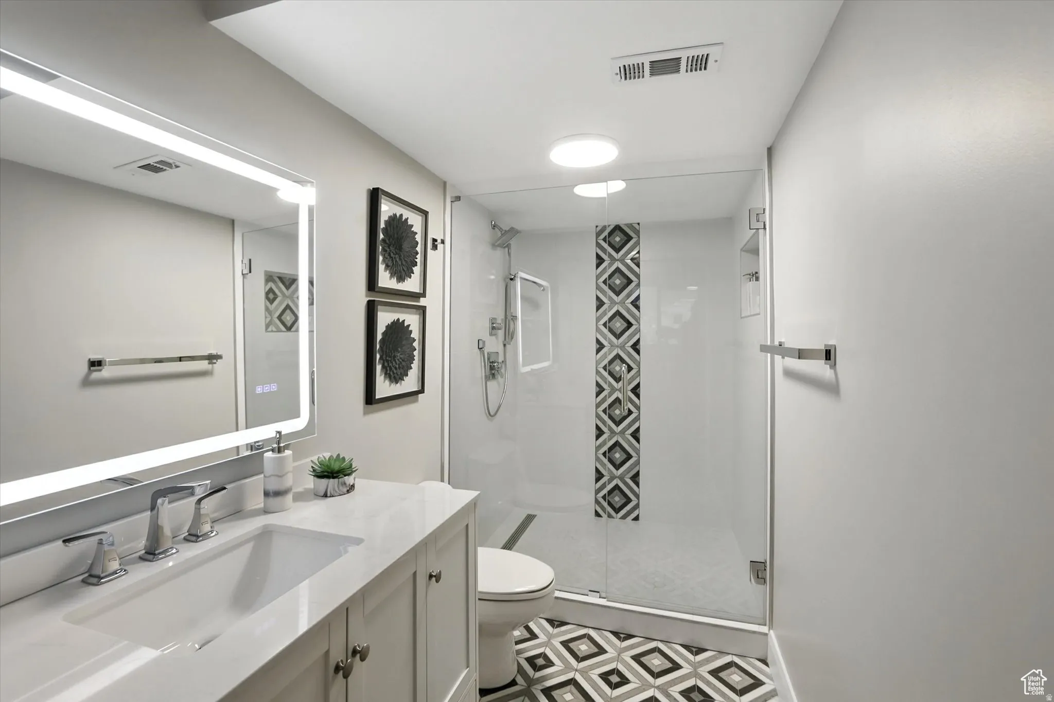 Bathroom suite on main level featuring vanity, a stall shower, and tile patterned floors