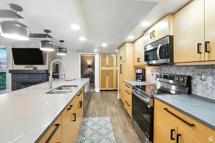 Kitchen featuring appliances with stainless steel finishes, wood finished floors, light brown cabinets, backsplash, and recessed lighting
