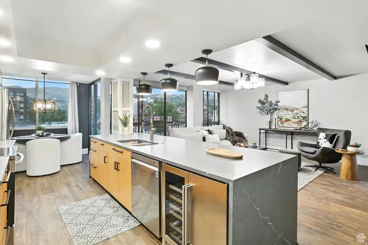Kitchen featuring beverage cooler, open floor plan, appliances with stainless steel finishes, and a waterfall countertop