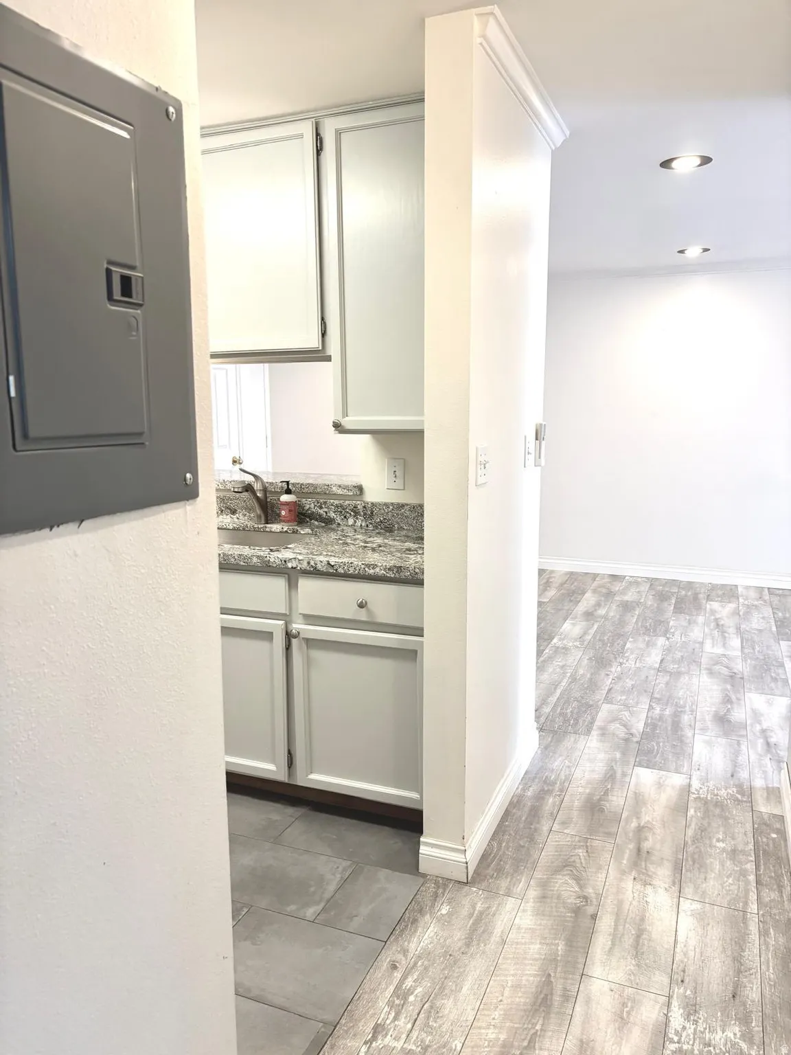 Kitchen featuring electric panel, light wood-style floors, and light stone counters