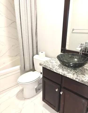 Bathroom with vanity, light marble finish flooring, and shower / tub combo with curtain