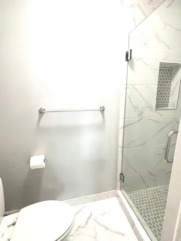 Bathroom featuring a marble finish shower and light marble finish flooring