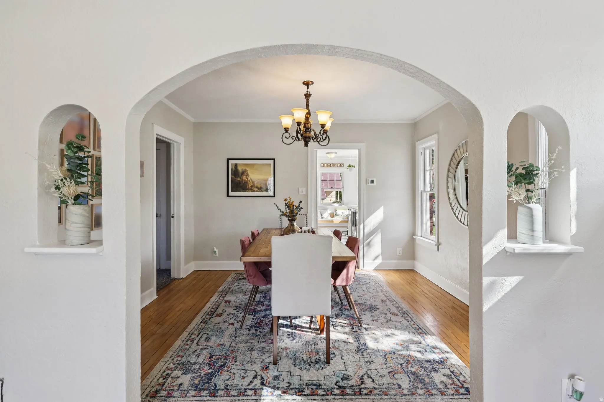 Dining room featuring hanging lights, arched walkways, light wood-type flooring, and crown molding