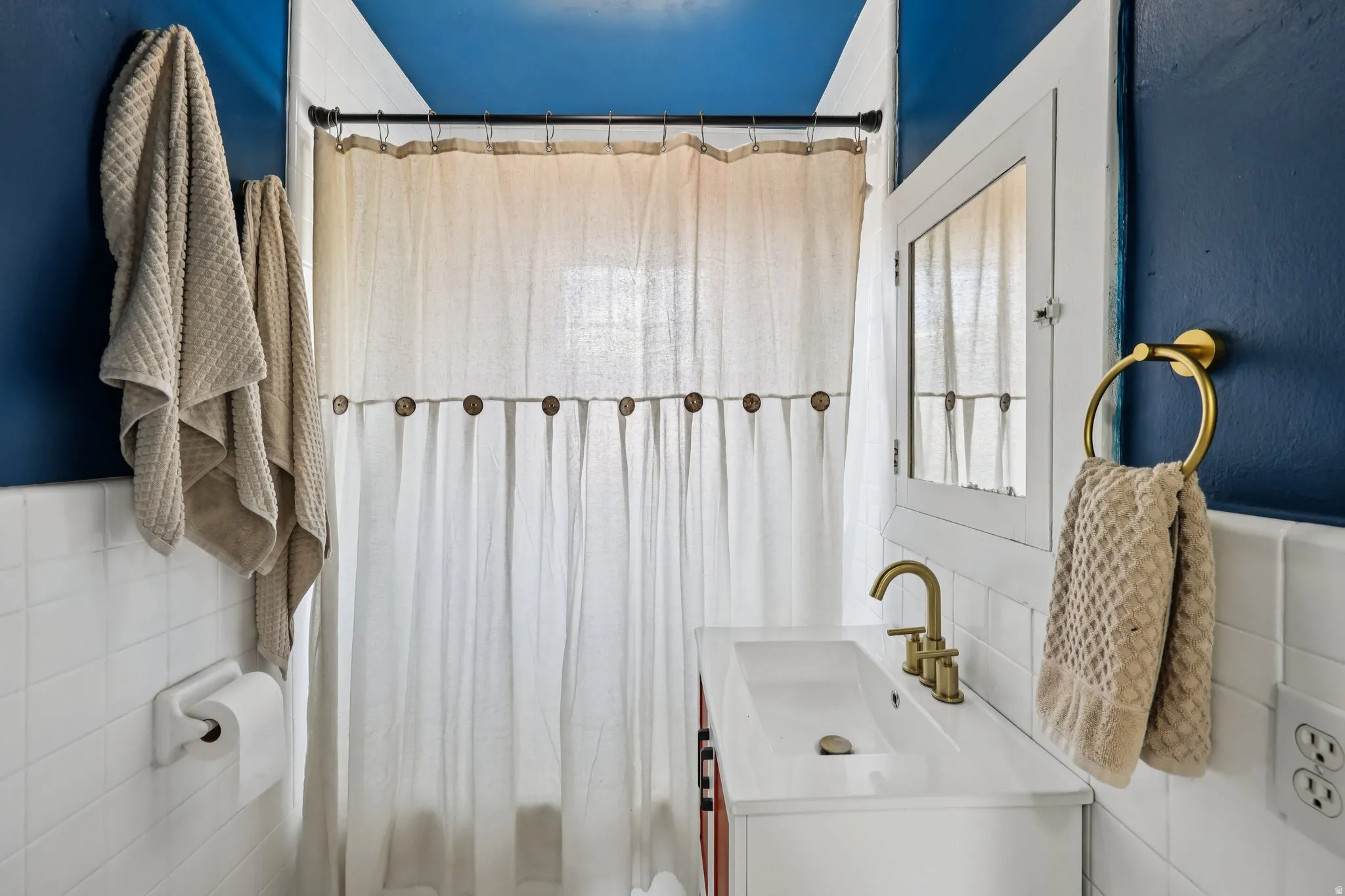 Bathroom featuring tile walls, vanity, and a shower with curtain