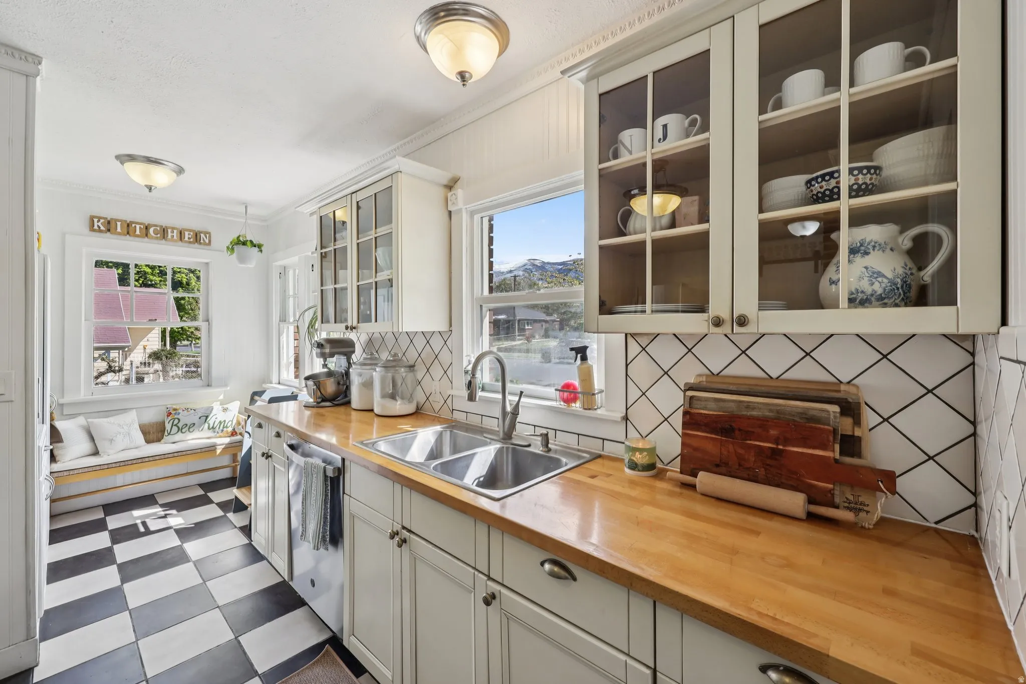 Kitchen featuring decorative backsplash, glass insert cabinets, dark flooring, wood counters, and stainless steel dishwasher