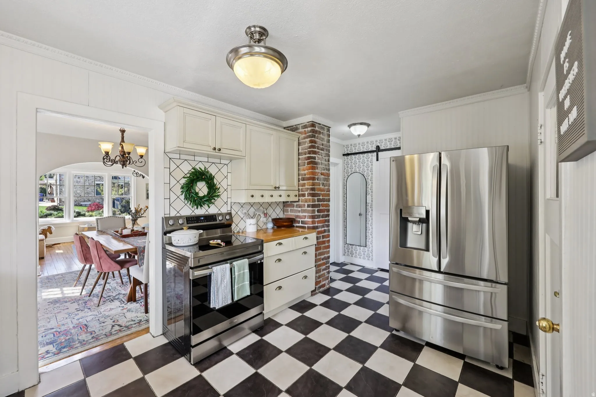 Kitchen with dark floors, stainless steel appliances, hanging lights, crown molding, and butcher block countertops
