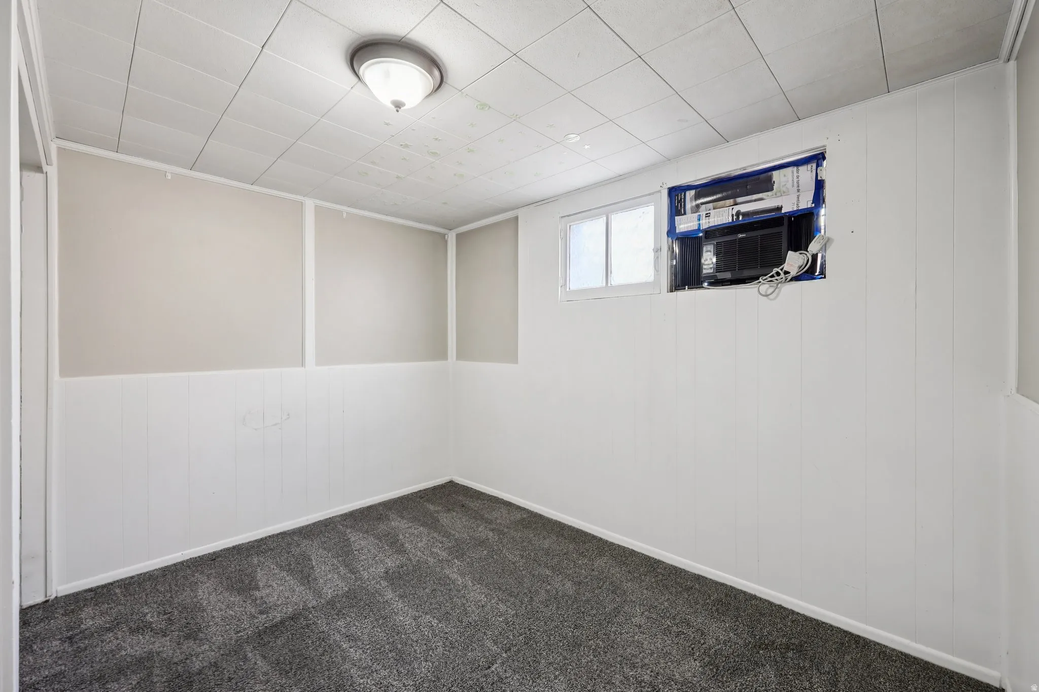 Basement featuring wooden walls, dark colored carpet, and a wainscoted wall