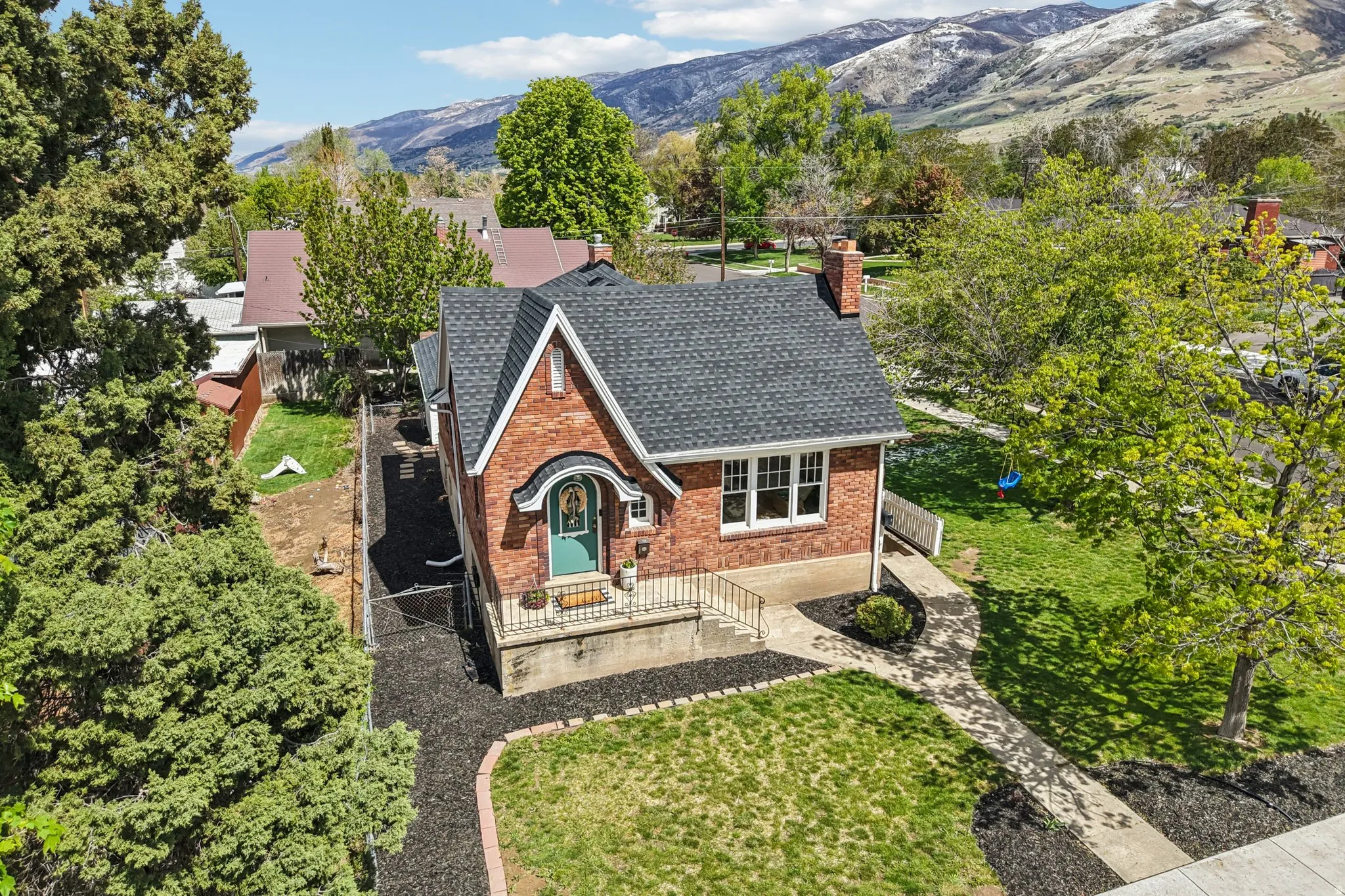 View of front of home with brick siding, a chimney, a mountain view, roof with shingles, and a front lawn